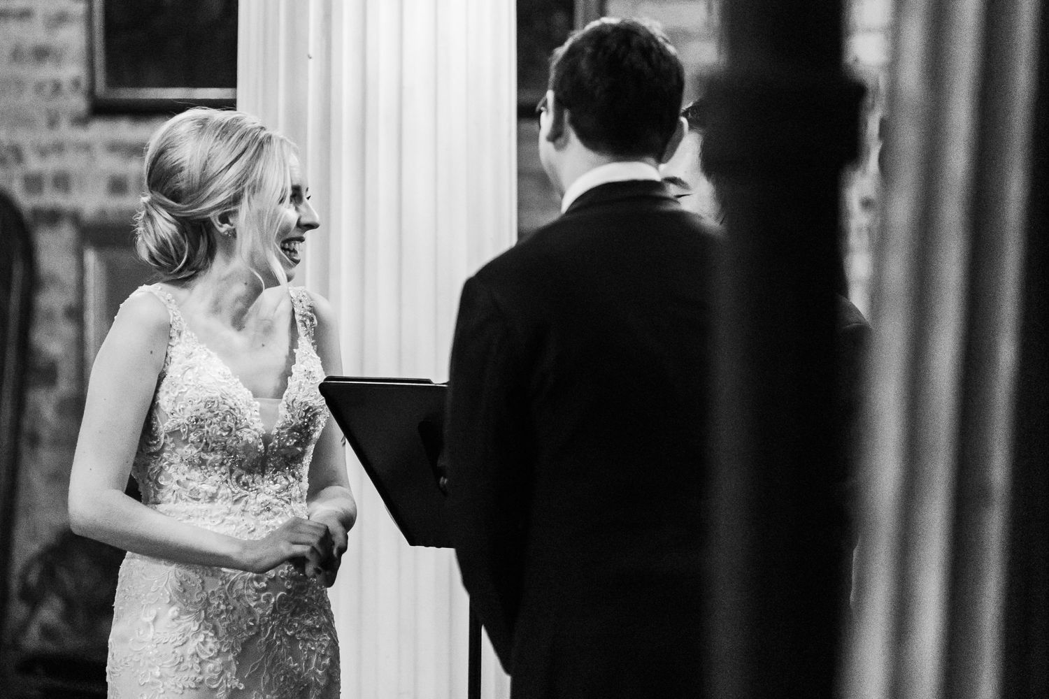 Black and white candid shot of couple during wedding ceremony in elegant interior.