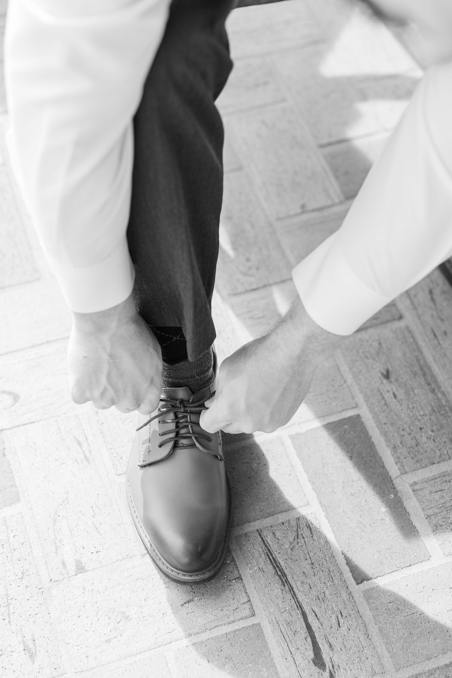 Black and white photo of a person putting on formal leather dress shoes.