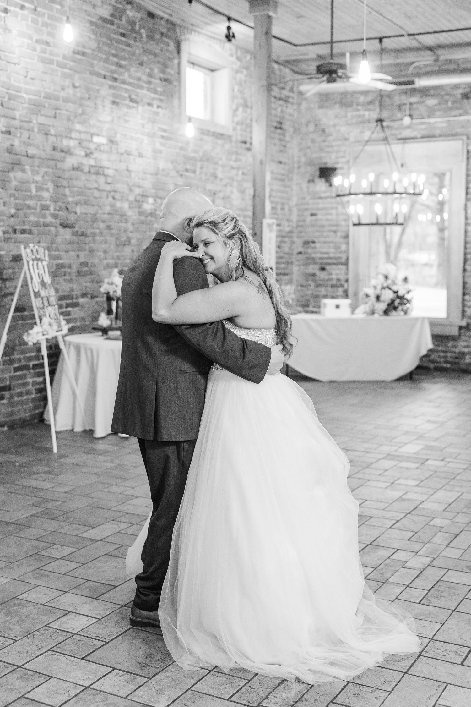 Black and white photo of couple sharing dance in industrial brick venue.