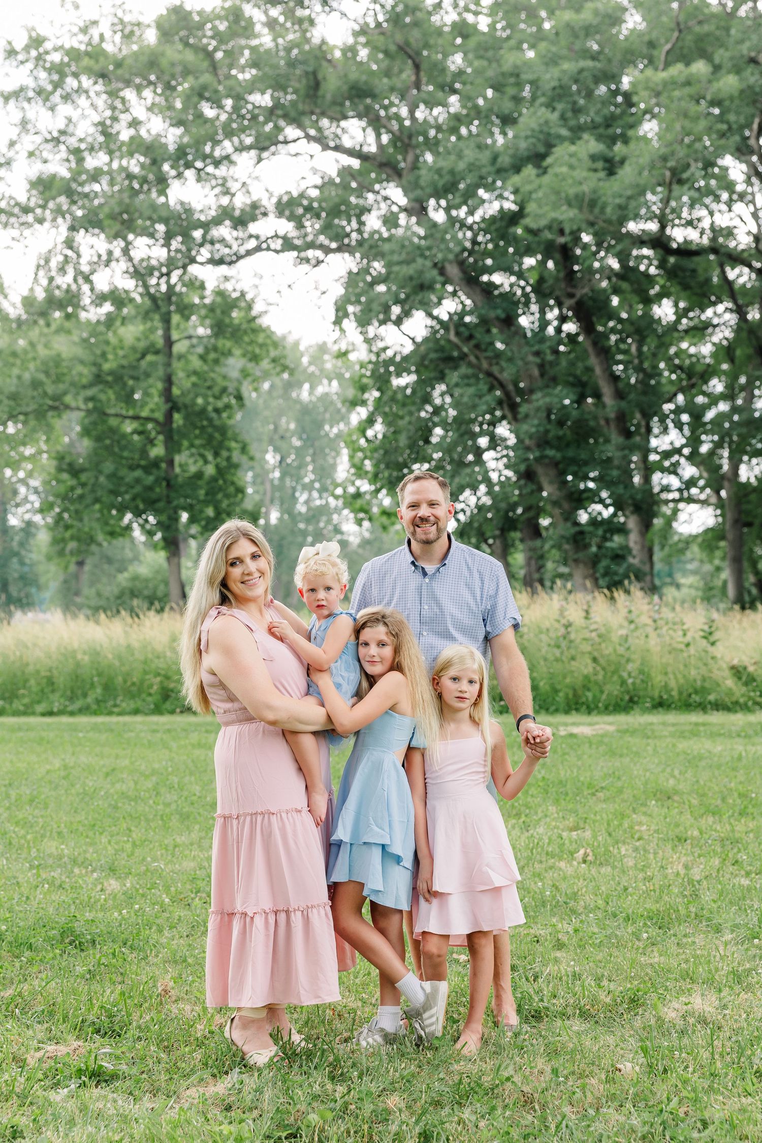 Parents and daughters smiling together during a bright summer family photo session in Crystal Lake, Illinois.