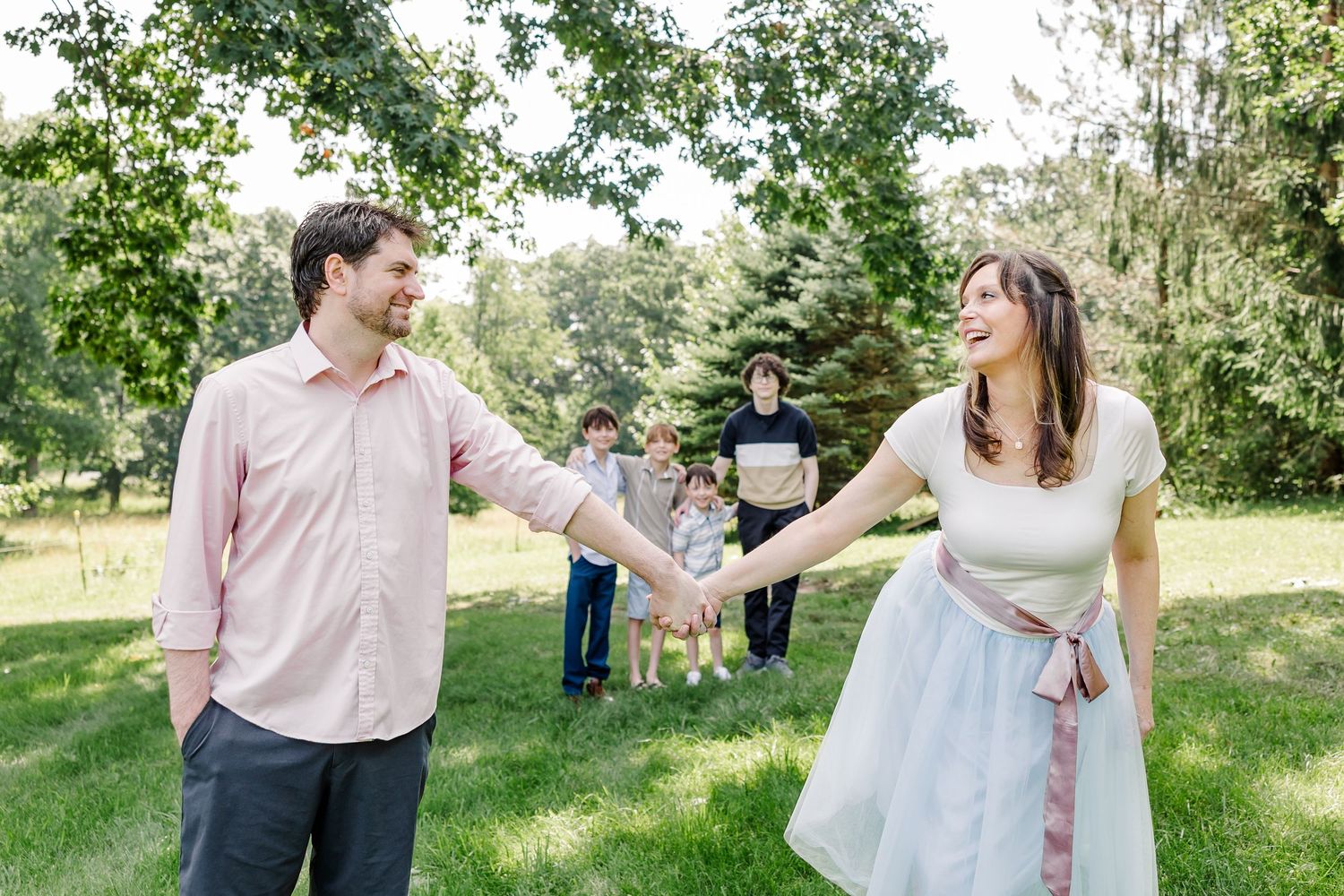Couple holding hands with family in the background during a summer extended family session in Crystal Lake, IL.