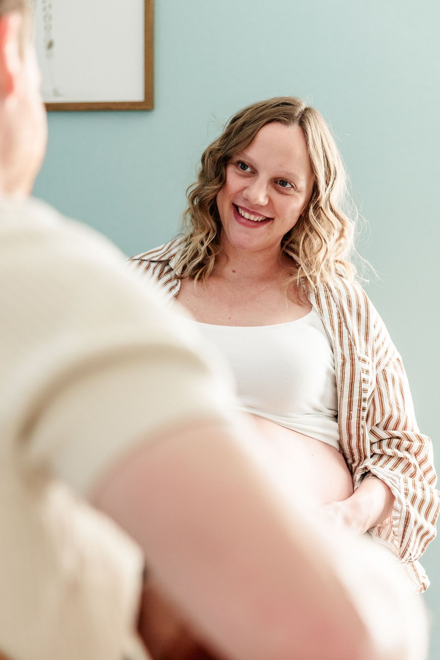 Mother smiling while father plays guitar during a cozy in-home maternity session in Crystal Lake, Illinois.