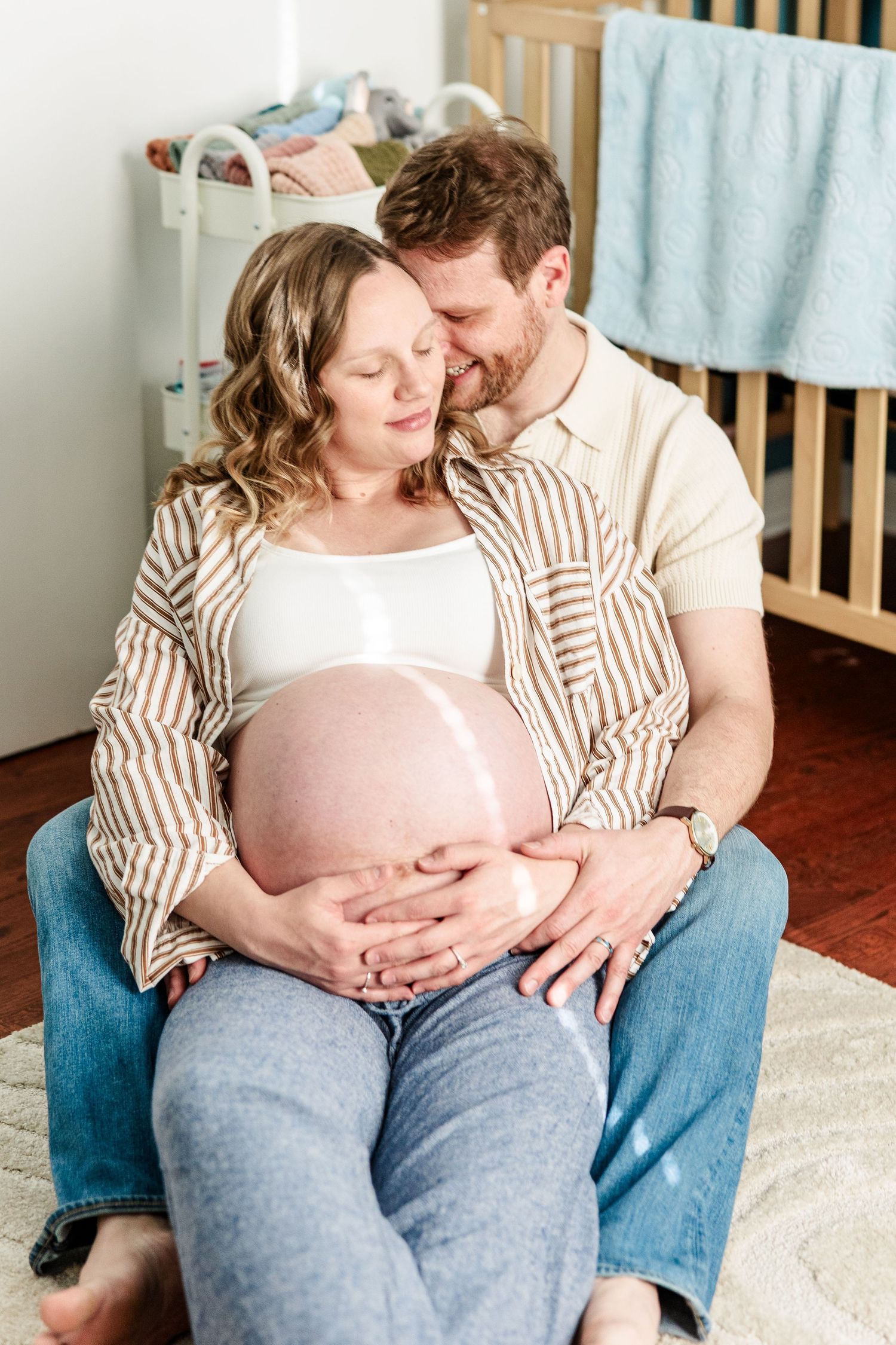 Expecting parents sitting together in the nursery during a cozy in-home maternity session in Crystal Lake.