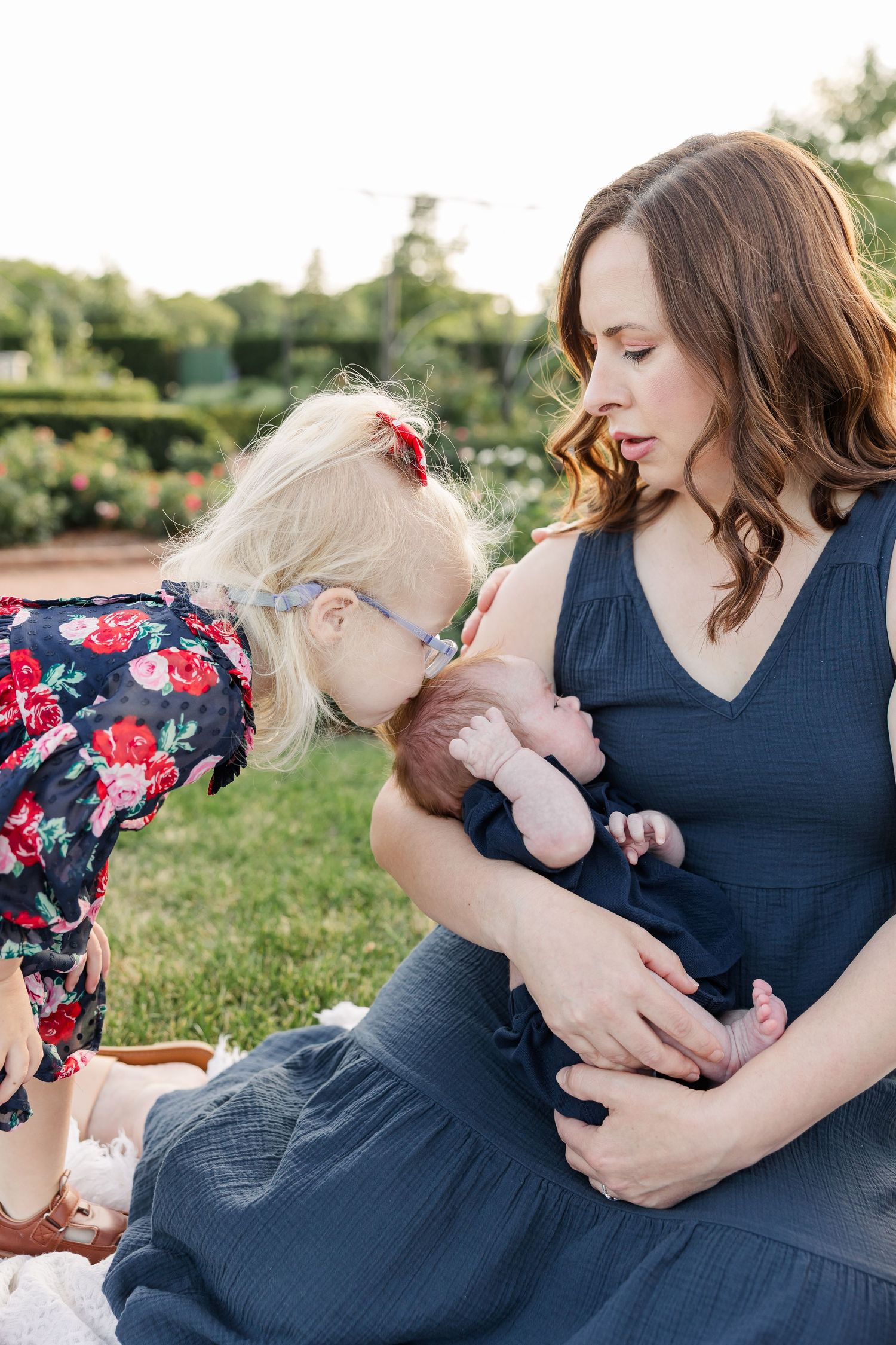 Caroline leaning in to kiss baby Lincoln as Hilary holds him during their outdoor family session.