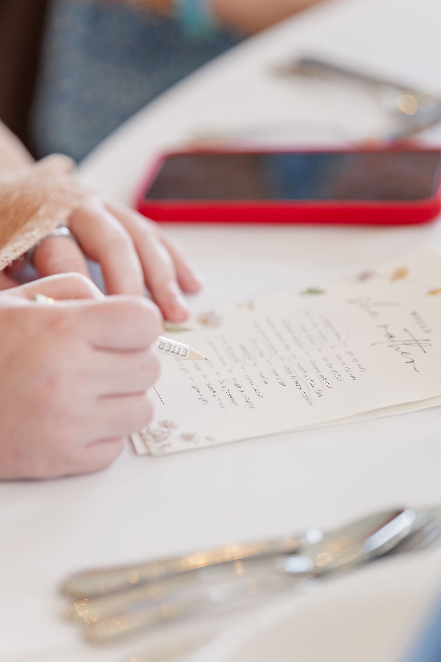 Close-up of guest hand writing well wishes at bridal shower table