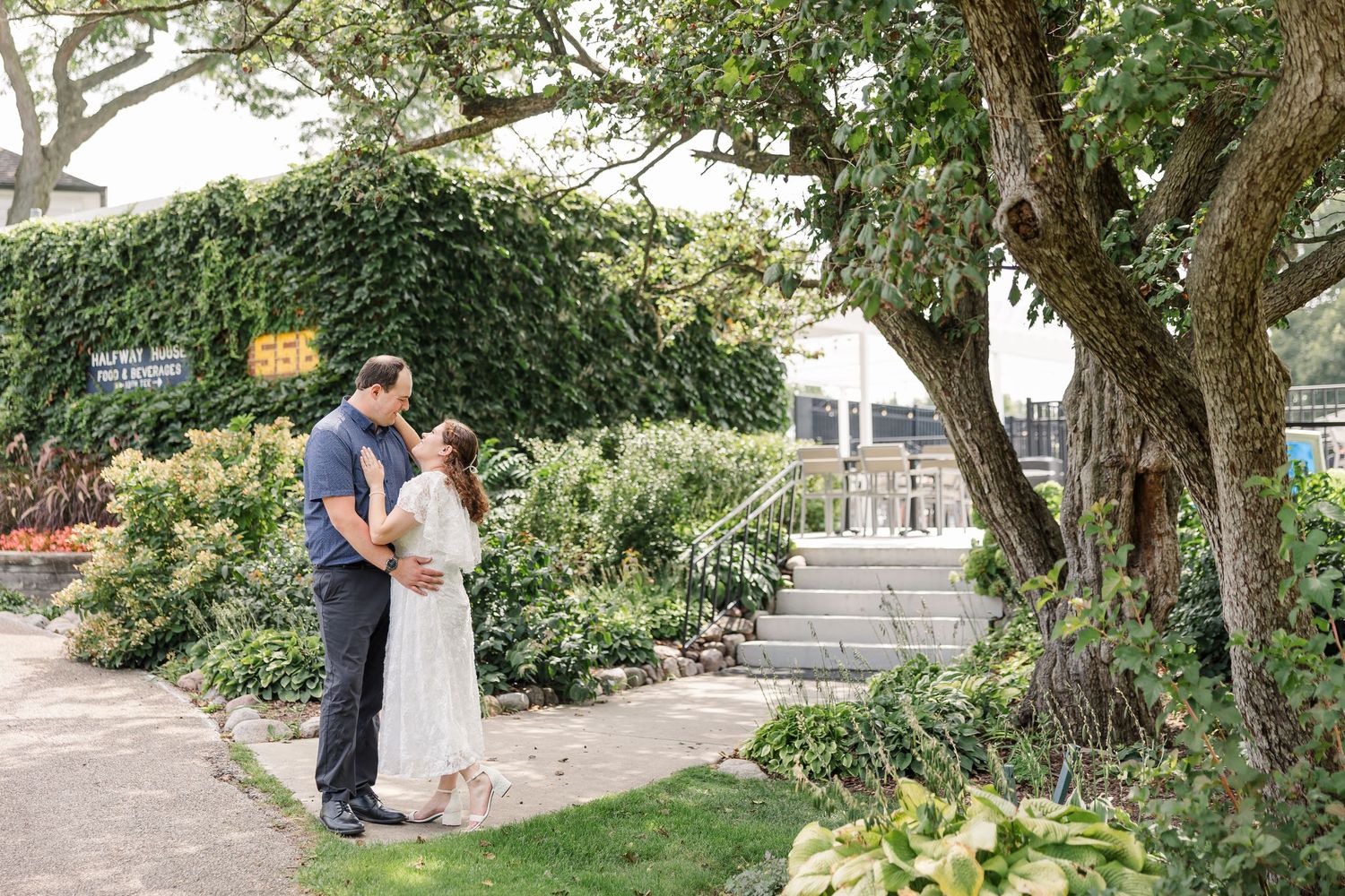 Couple sharing a romantic moment in a lush garden surrounded by ivy-covered walls and greenery.