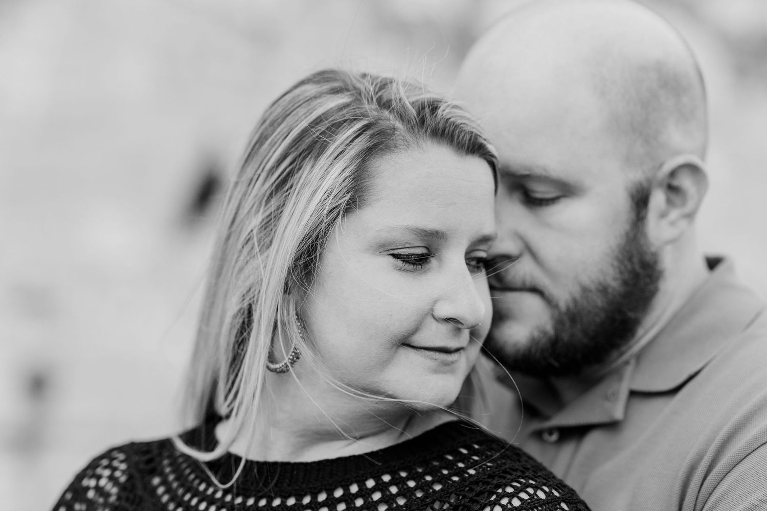 A black and white intimate portrait of a couple sharing a tender moment.