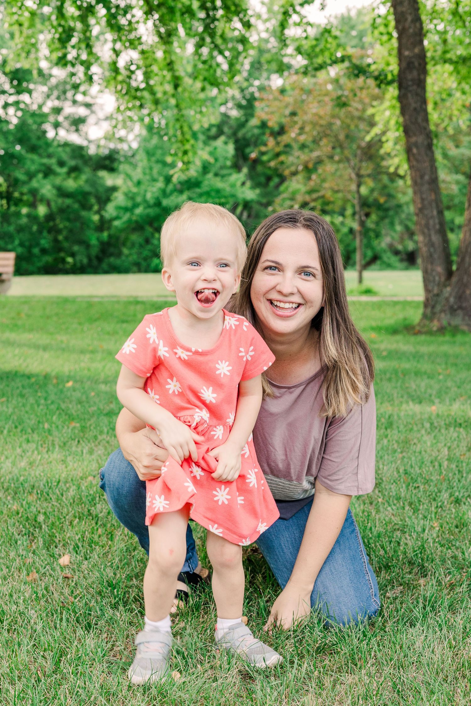 Mother and young child in coral dress share happy smiles during outdoor photo session.