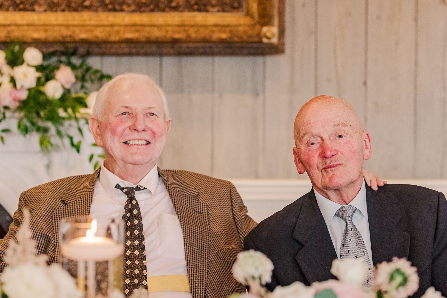 Two senior gentlemen sharing laughs at formal dinner table.