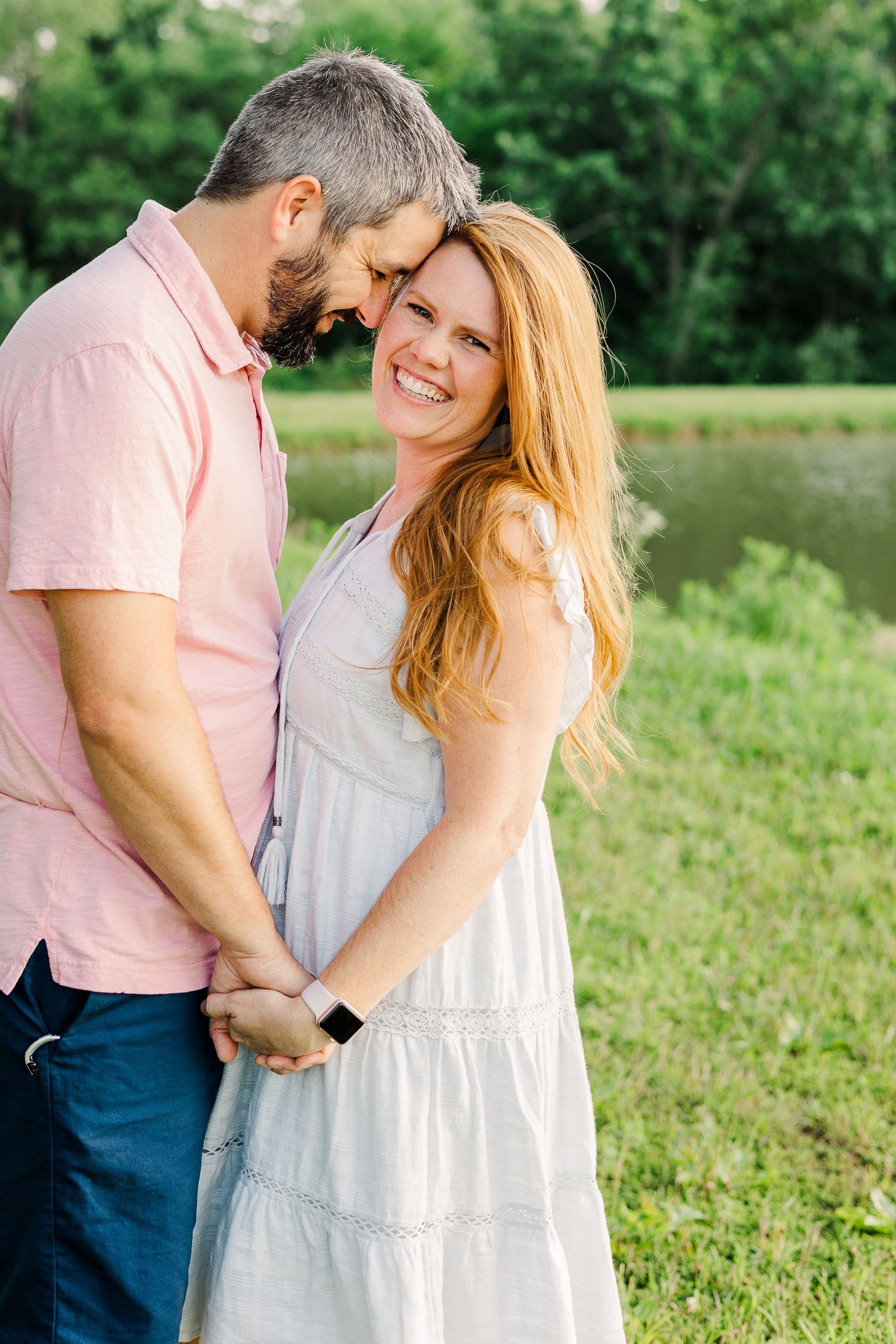 Tender embrace between couple in casual attire by waterside.