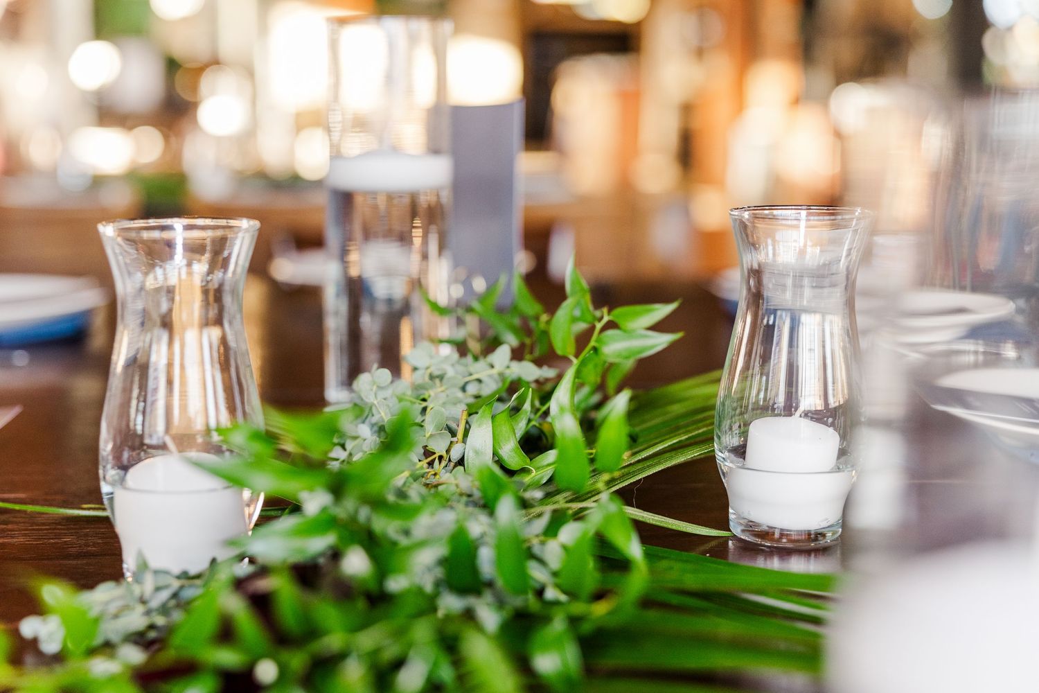 Table decor featuring glass vases and fresh greenery arrangements for an event.