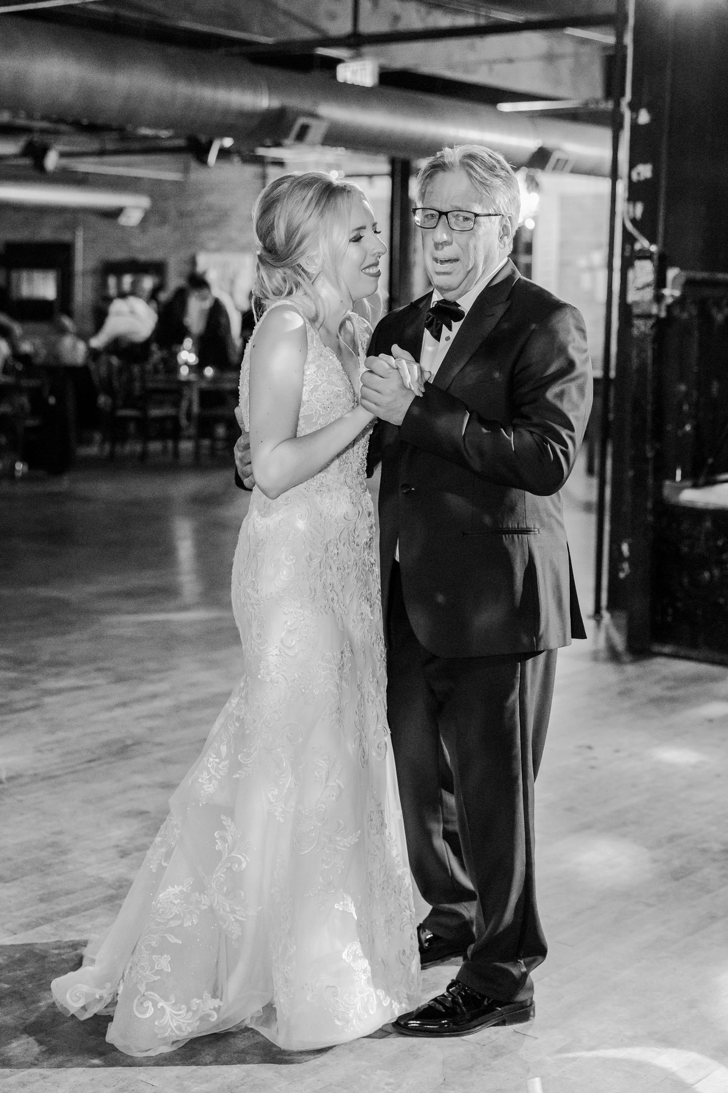 An emotional dance moment captured in black and white at an industrial wedding venue.