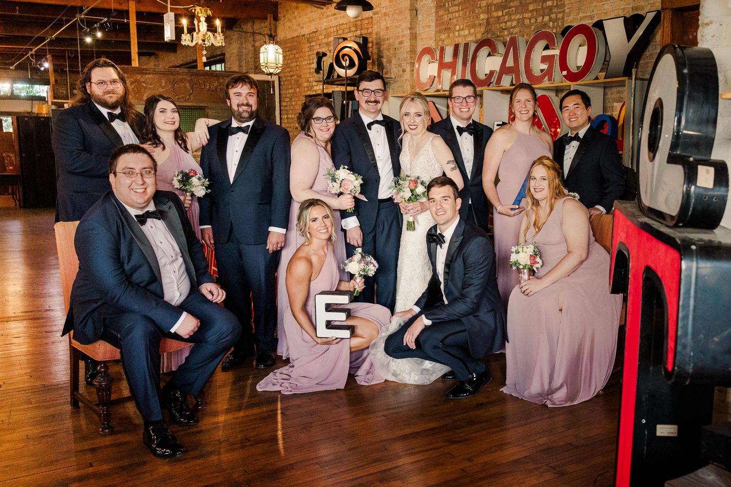 Wedding party poses casually in vintage Chicago-themed venue with industrial decor.