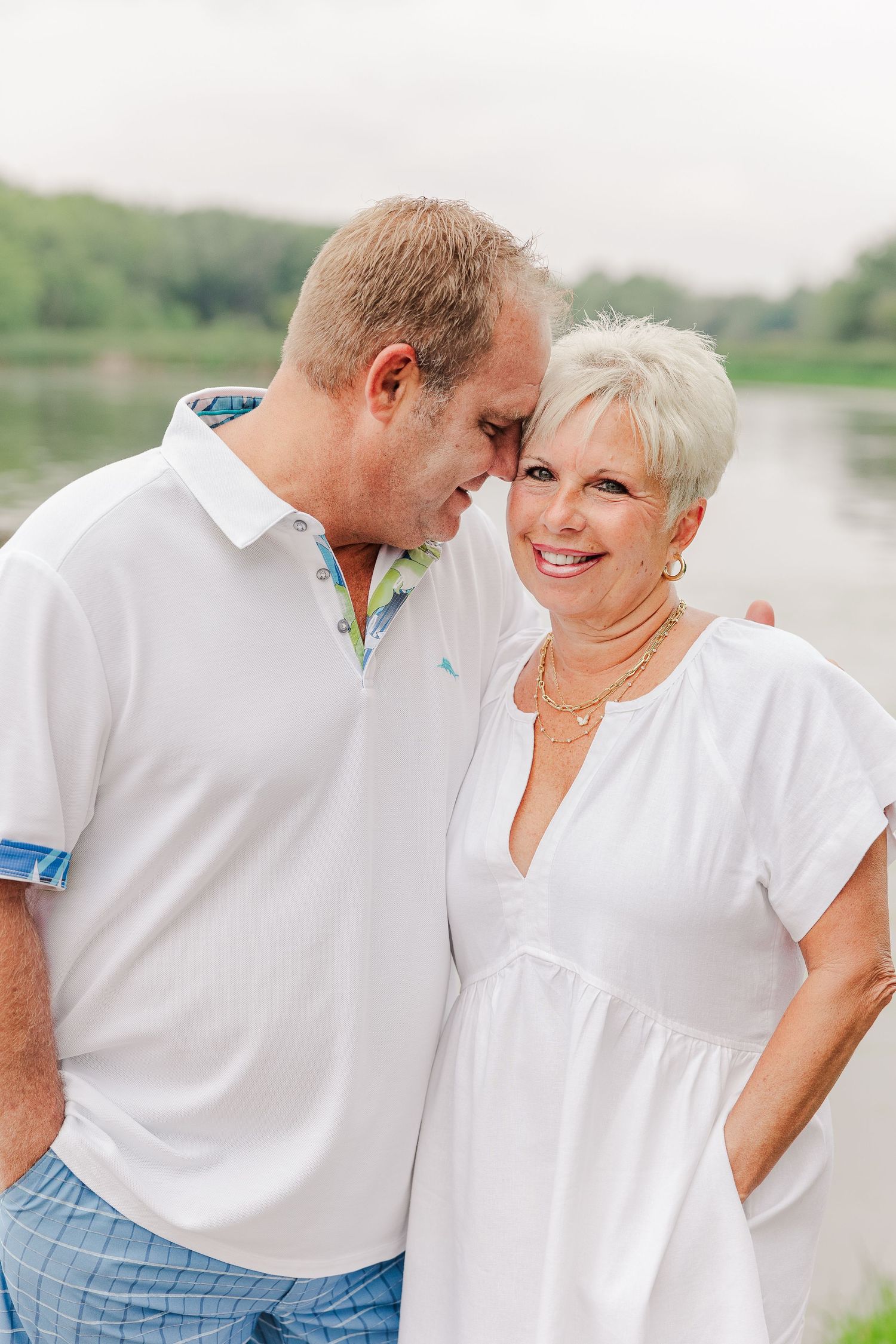 Couple shares tender moment on lakeside dock during summer photo session.