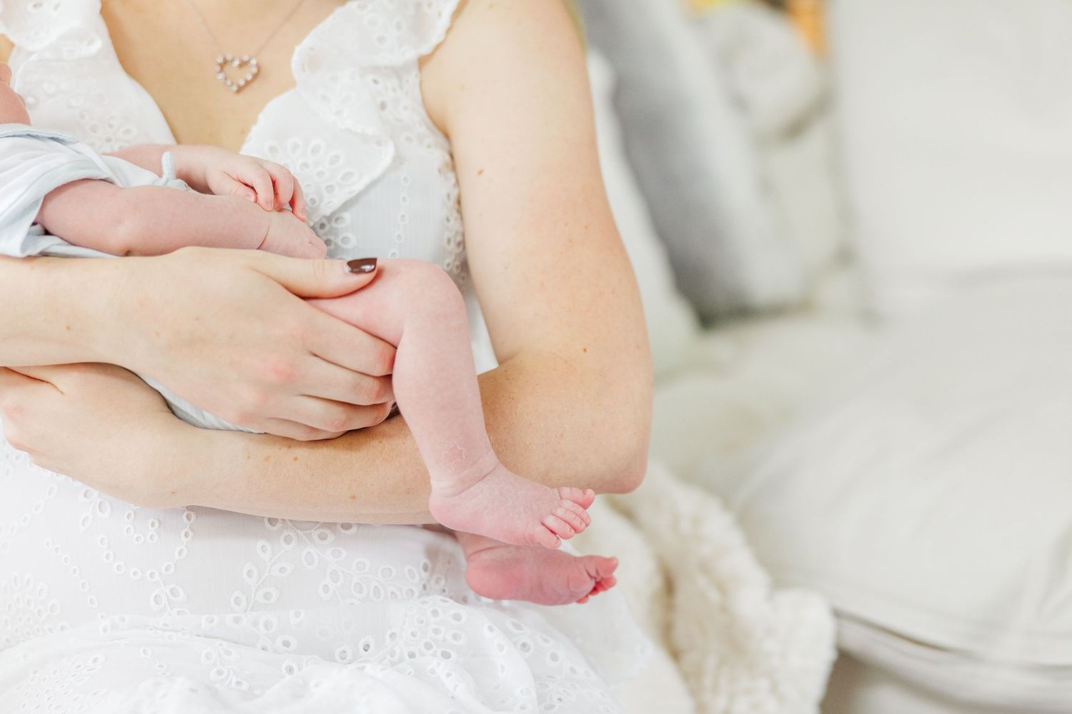 Newborn baby detail of tiny legs and hands while being held by mother during an in-home lifestyle newborn session in Vernon Hills IL