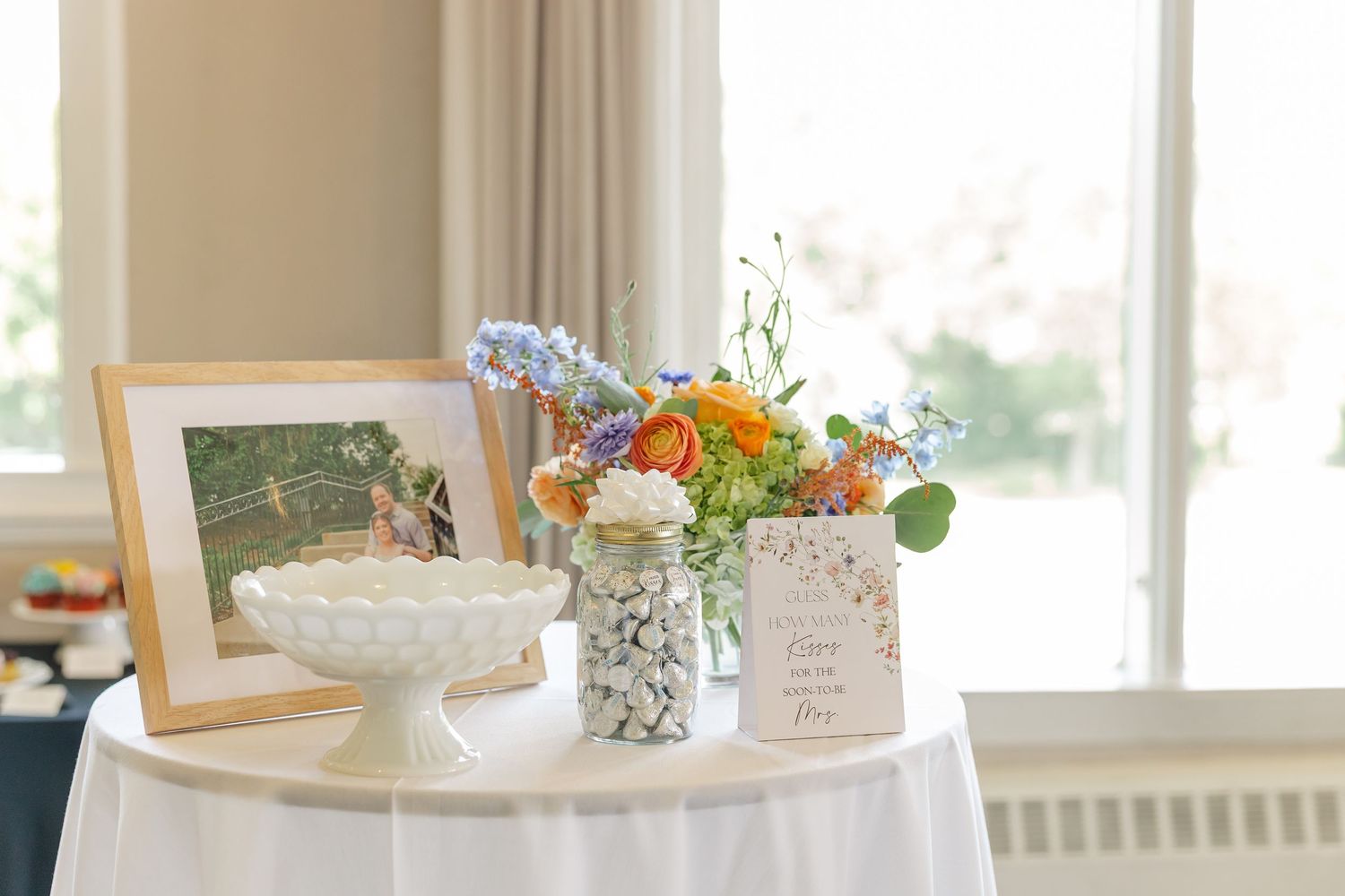 Framed photo and wildflower centerpiece on gift table at bridal shower