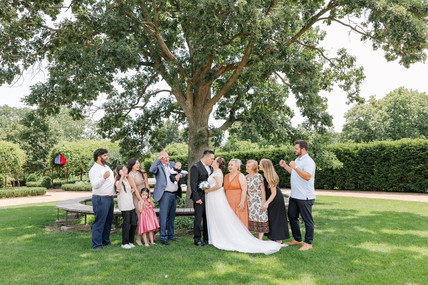 Bride and groom surrounded by their family during wedding portraits in the gardens at Cantigny Park.