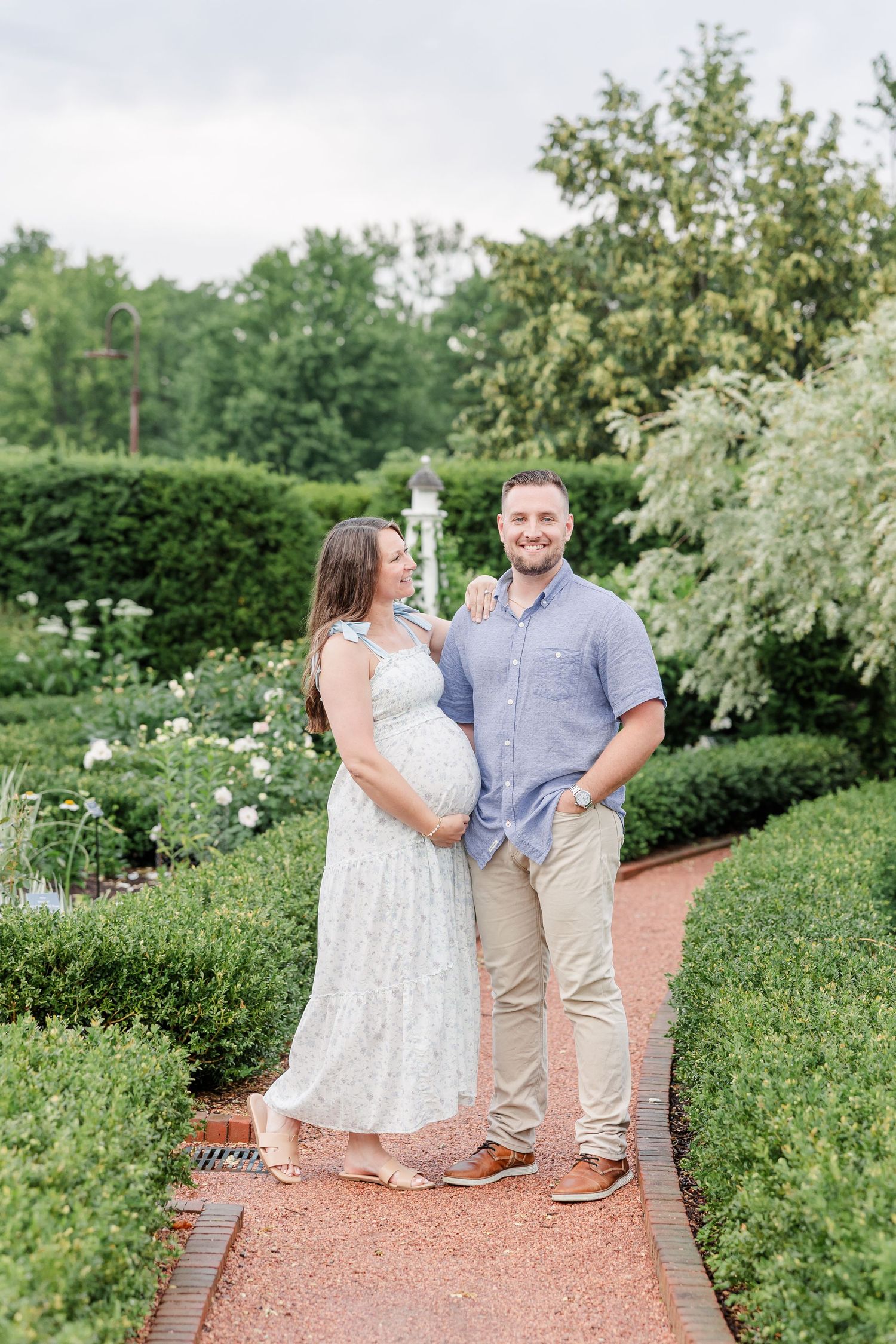 Expecting parents standing together in a quiet garden during a Cantigny Park maternity session