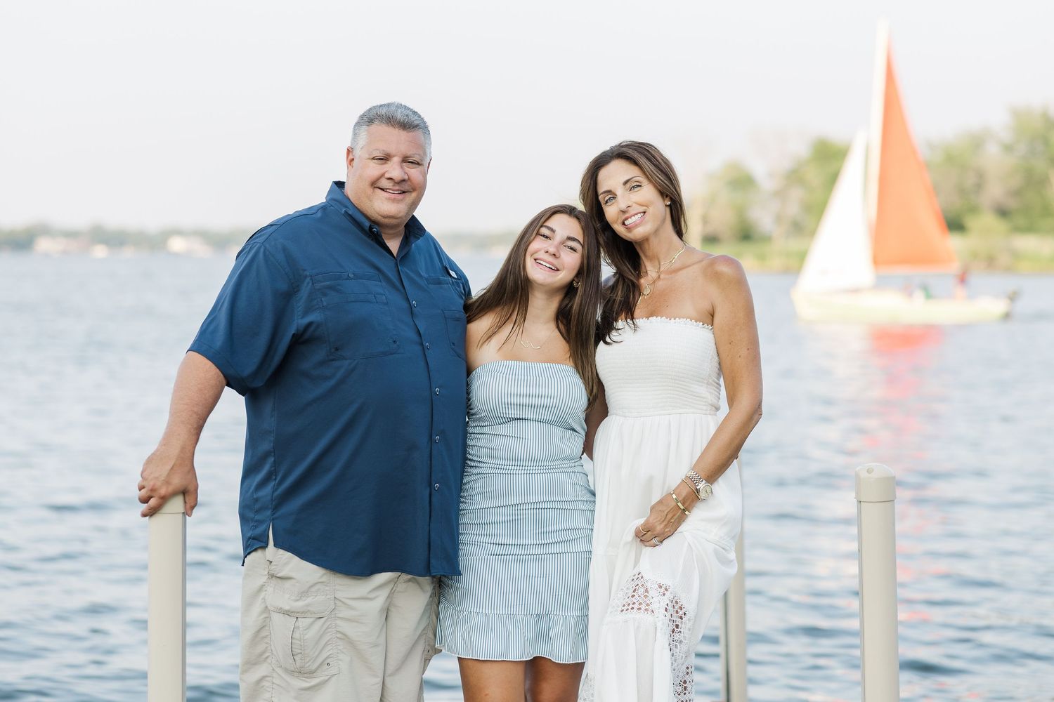 Family portrait on dock with sailboat during Pistakee Lake family photos in Johnsburg, Illinois