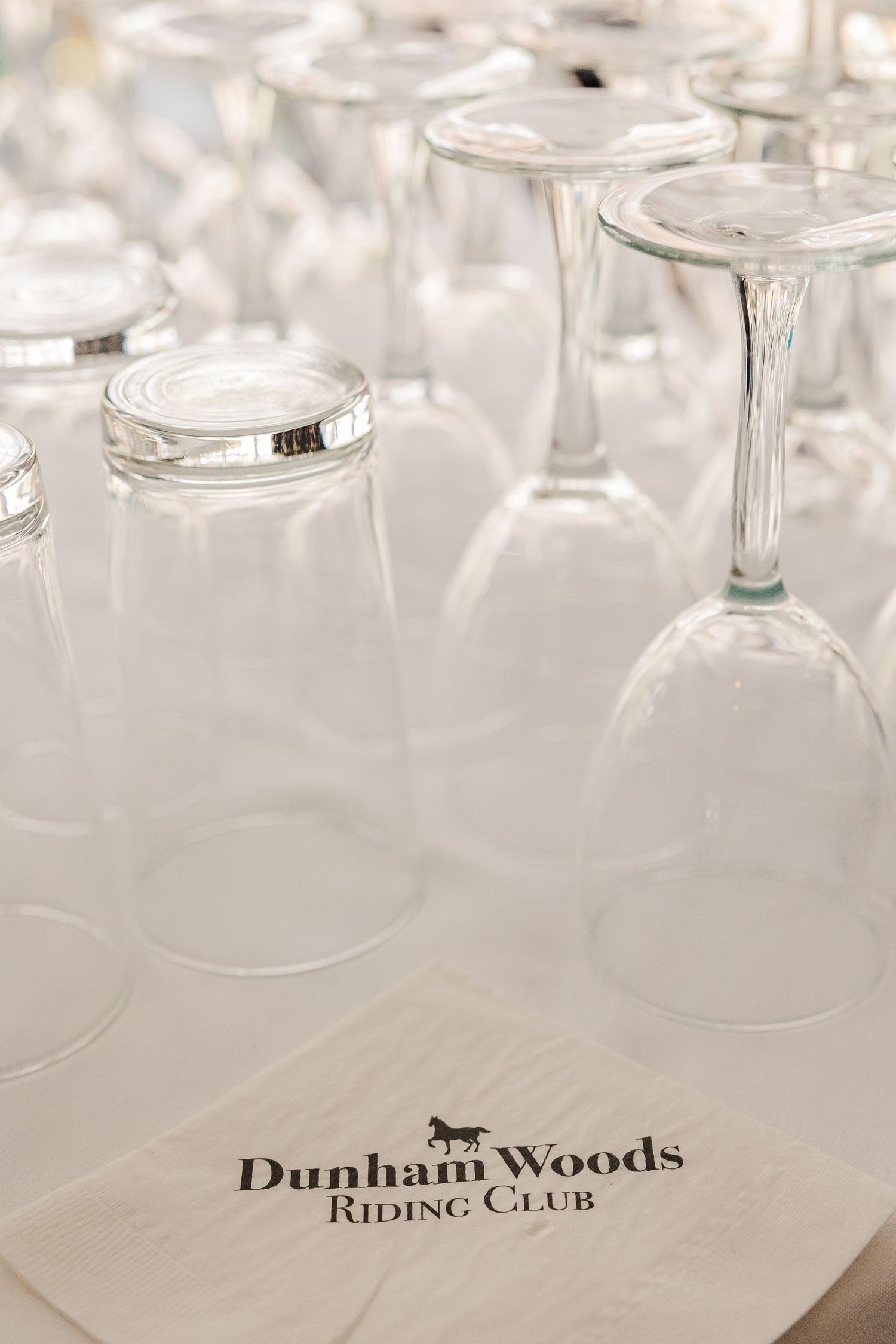 Wine glasses arranged upside down with Dunham Woods Riding Club branding visible.