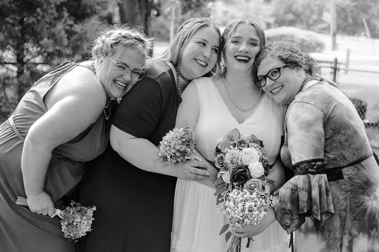 Black and white photo of bridesmaids laughing together while holding bouquets.