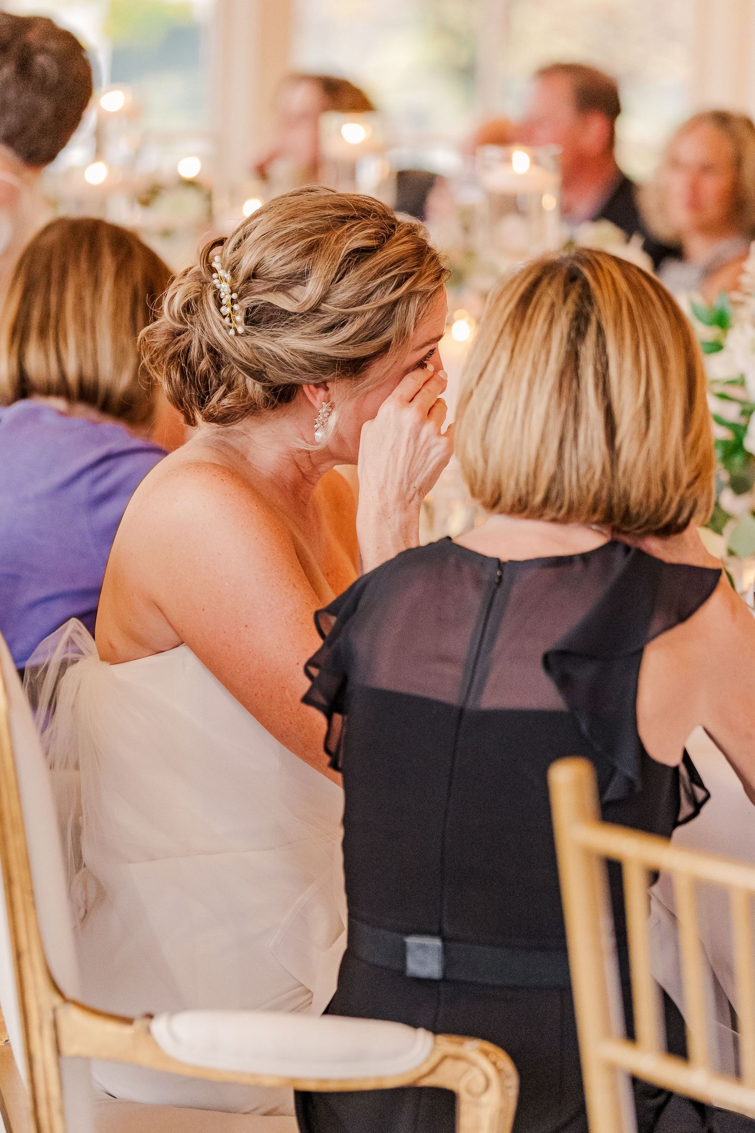 Two guests whispering and sharing secrets during wedding reception.
