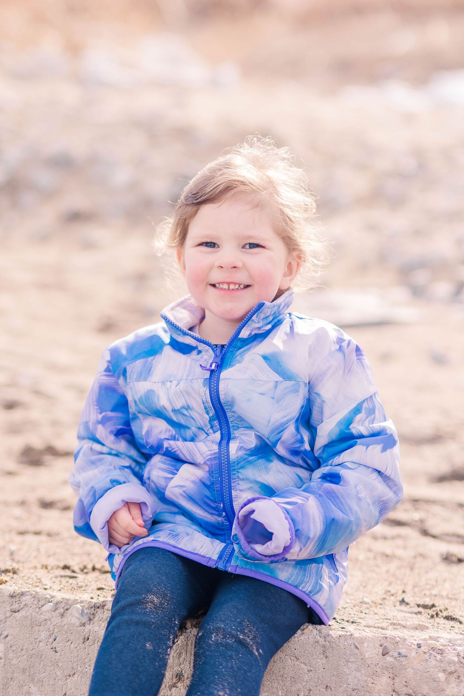 A joyful moment captured on a beach with someone wearing a blue tie-dye winter jacket.