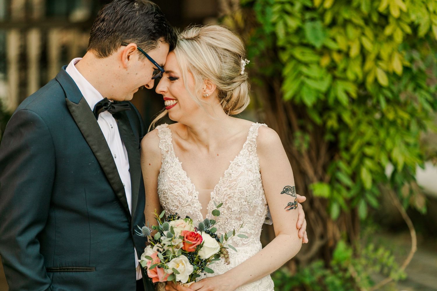 A tender moment shared between newlyweds against a backdrop of green foliage.