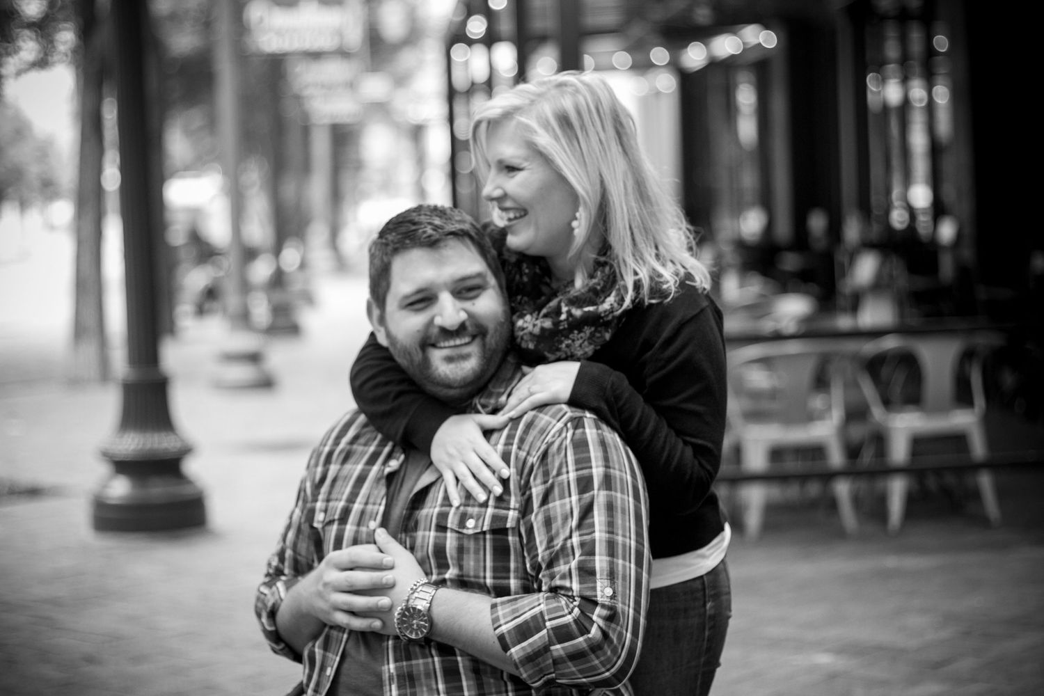 Black and white candid engagement photo with urban background.