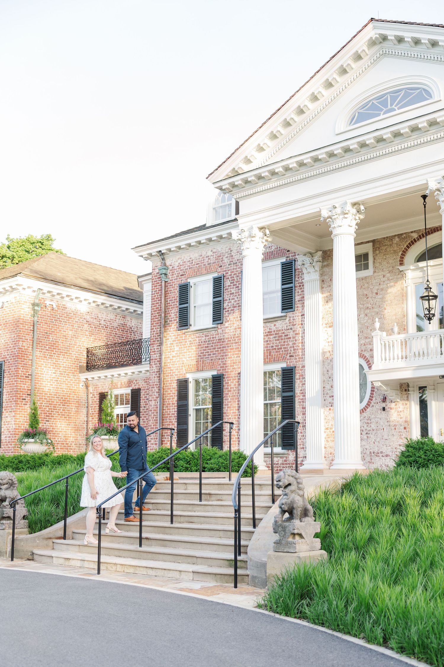 Elegant brick mansion with white columns and stairs leading to grand entrance.