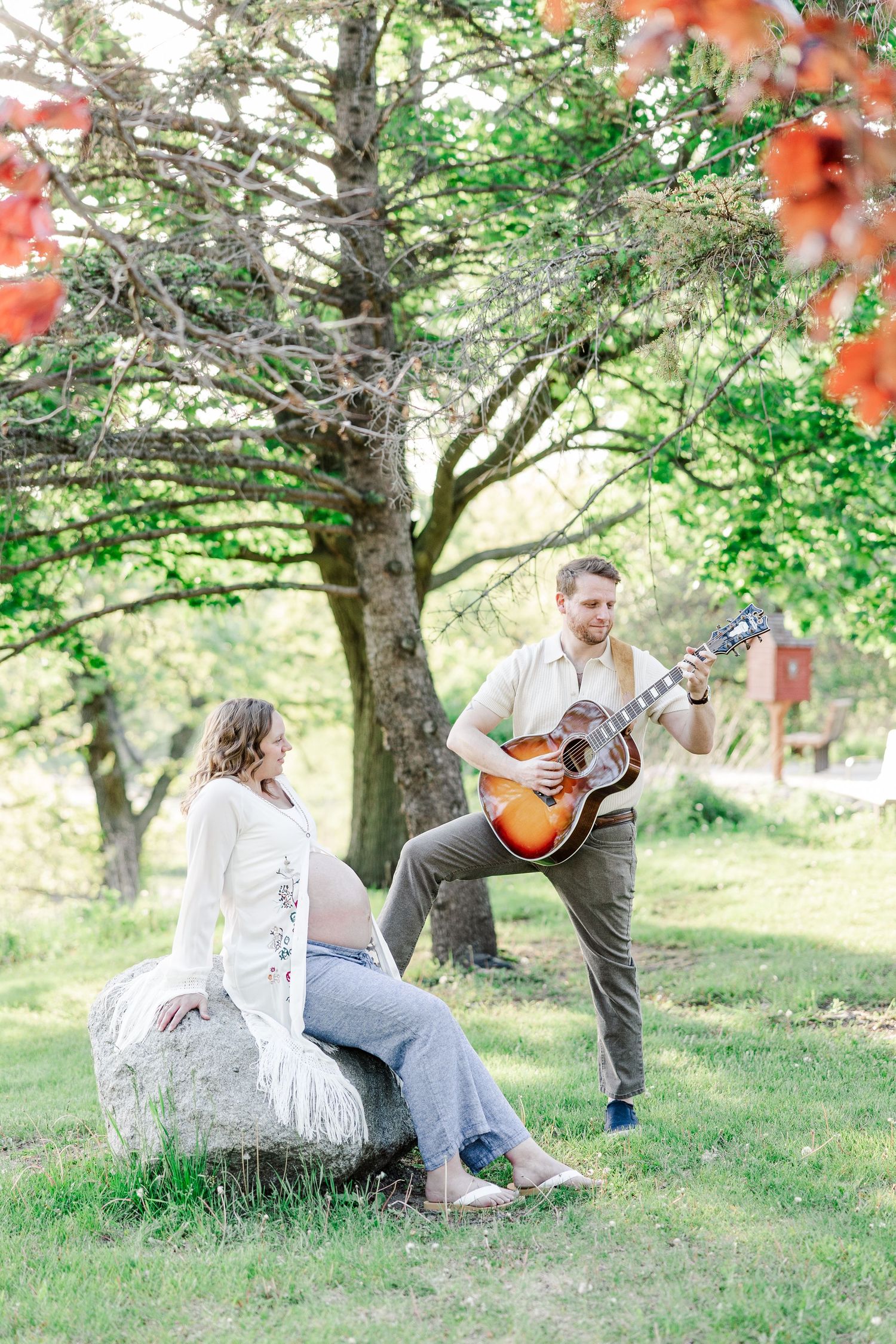 Father playing guitar for mother during a maternity session at Veterans Acres Nature Center in Crystal Lake, IL.