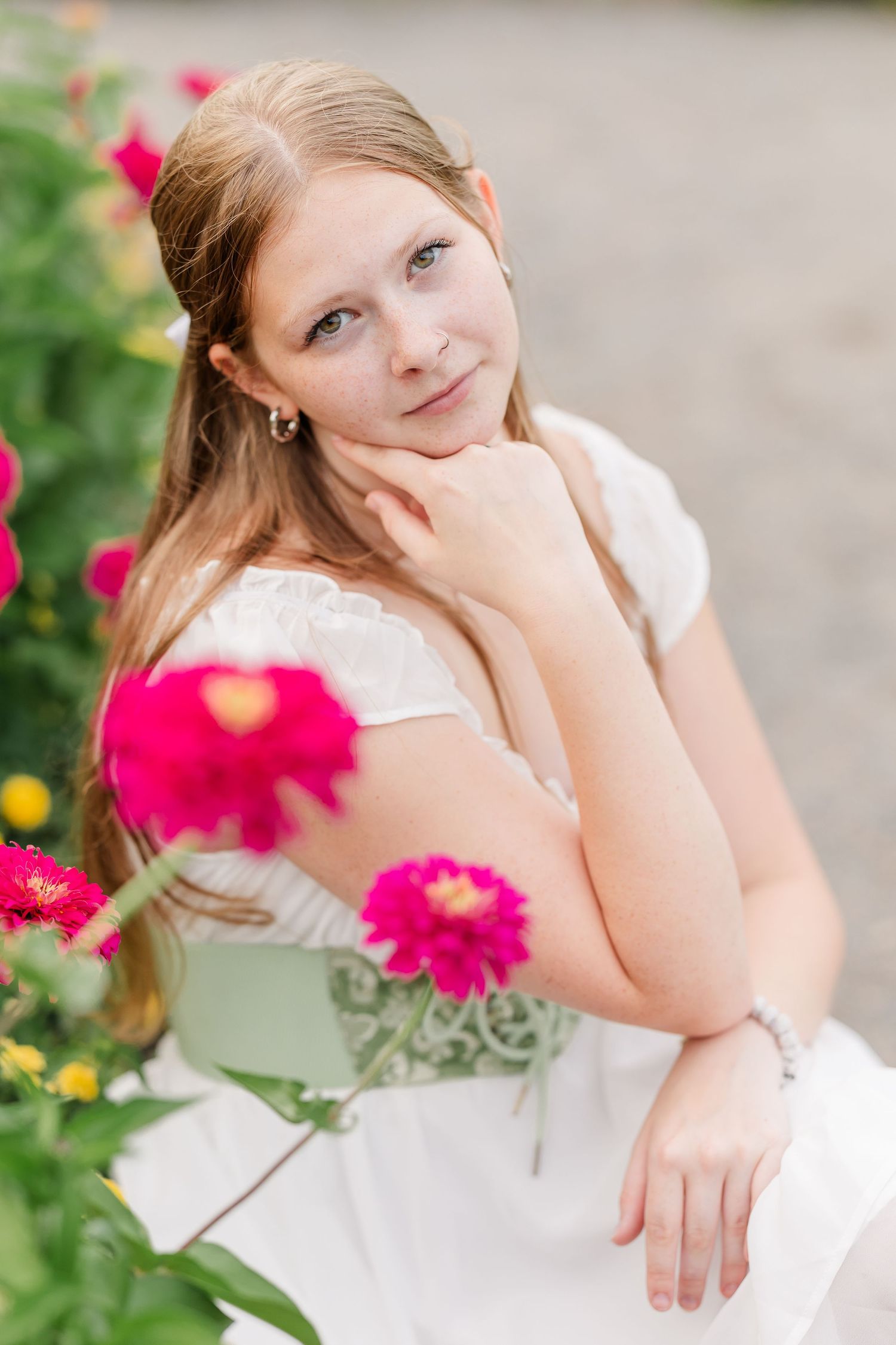 Close-up senior portrait of Samantha framed by bright pink flowers in the Cantigny Park gardens.