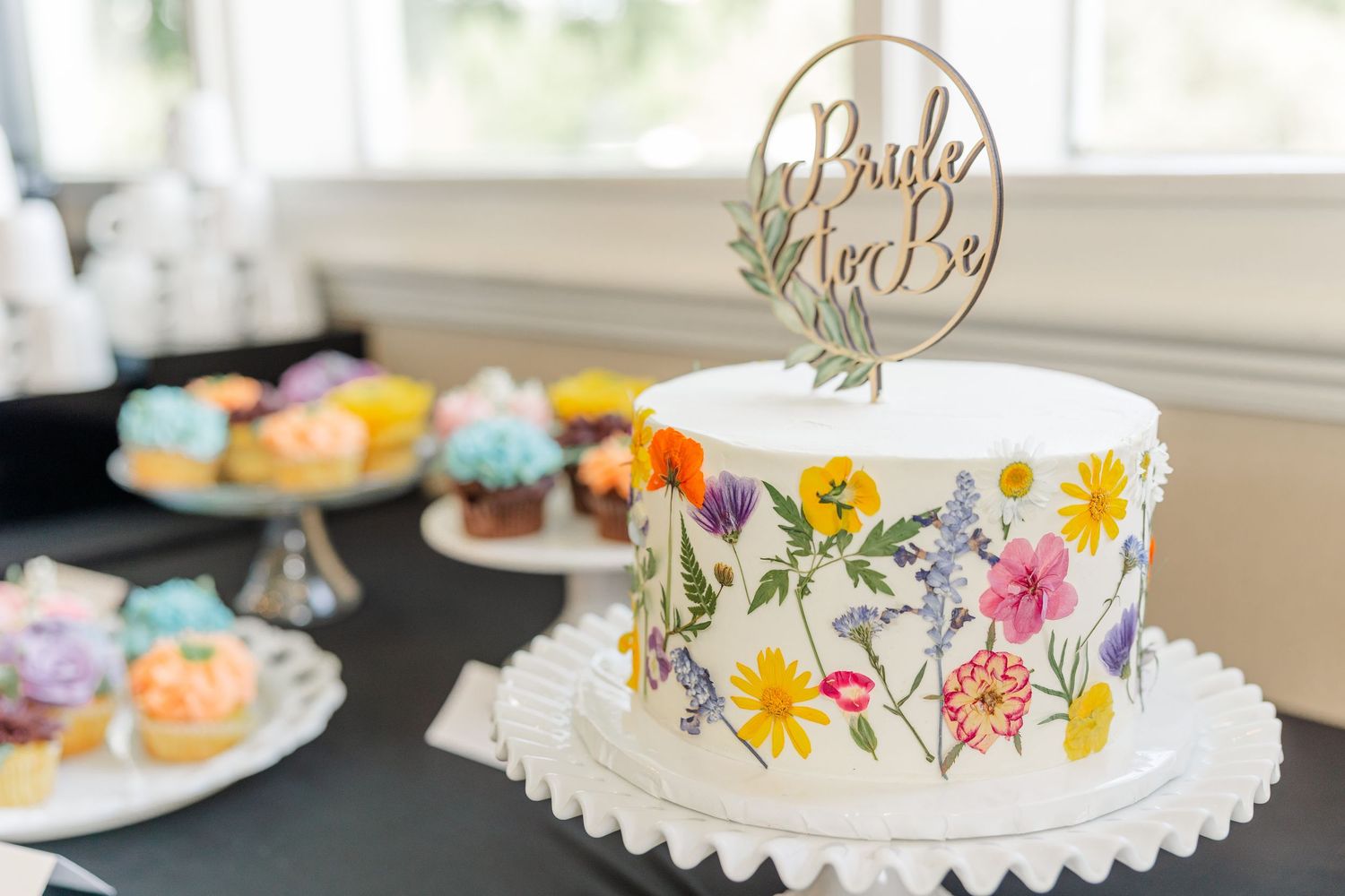 Bridal shower cake display with pastel cupcakes and Bride to Be topper