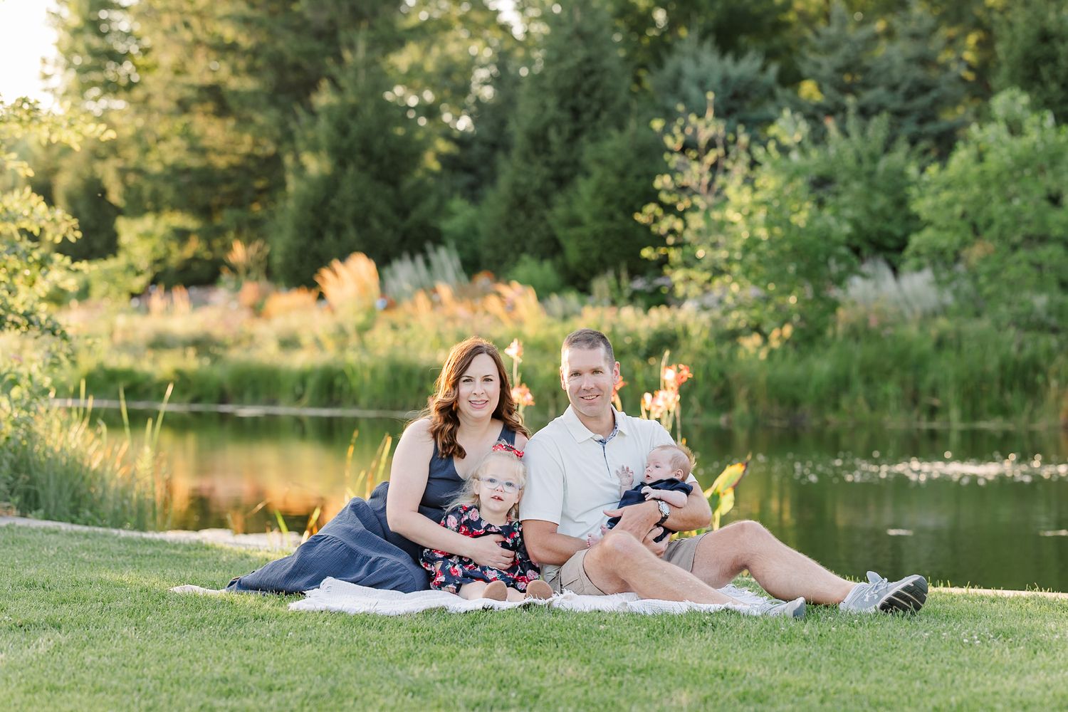 The Lawler family sitting together on a blanket beside the pond at Cantigny Park.