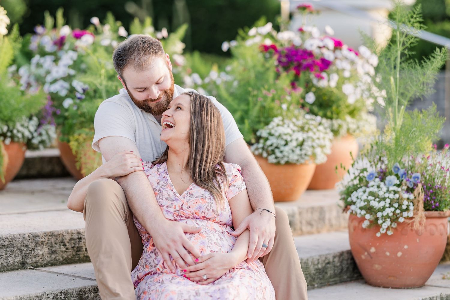 Expecting parents cuddling on garden steps during a romantic Cantigny maternity session in Wheaton Illinois