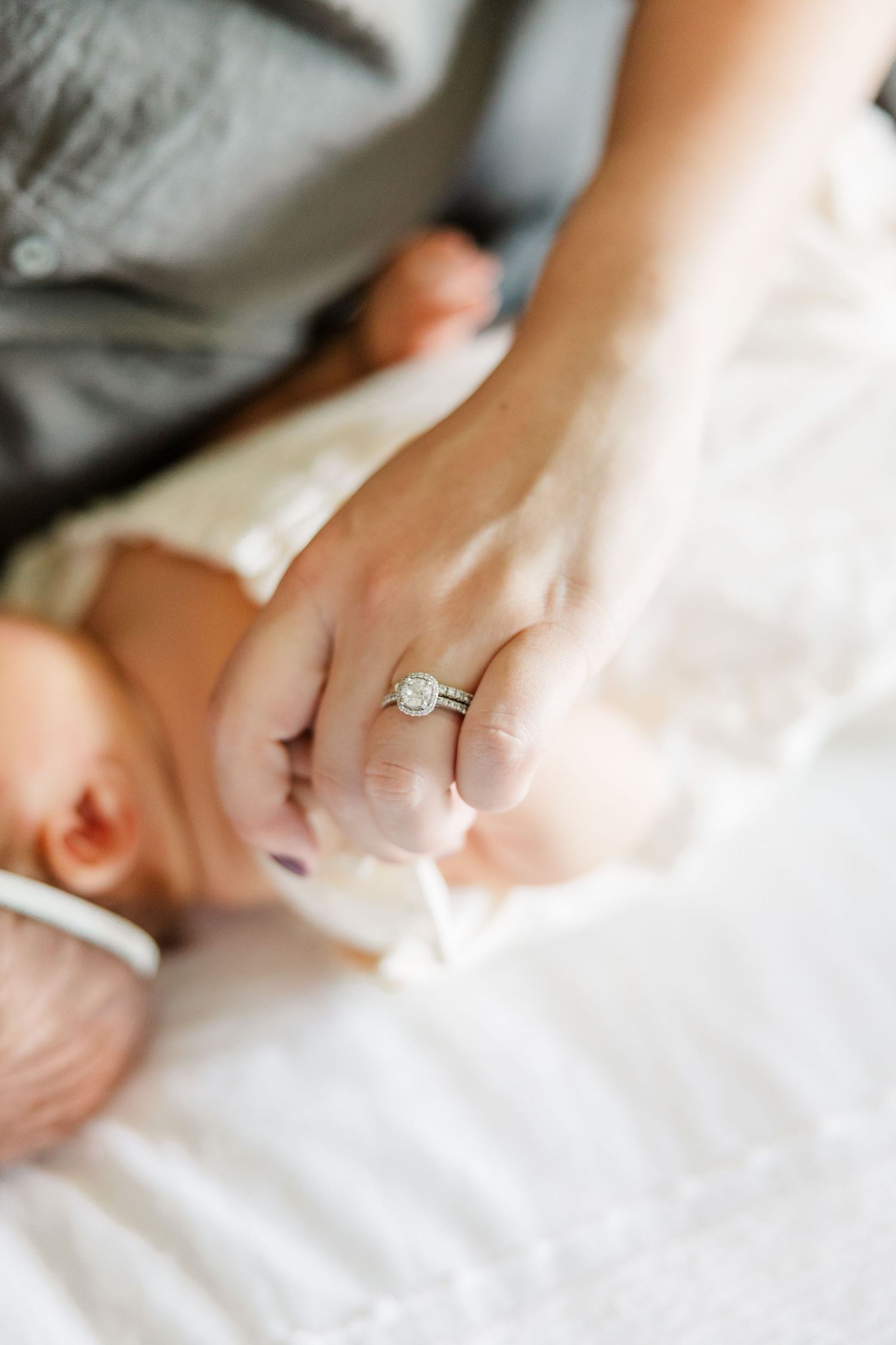 Close-up of parents holding newborn baby girl’s tiny hand during an in-home lifestyle newborn session