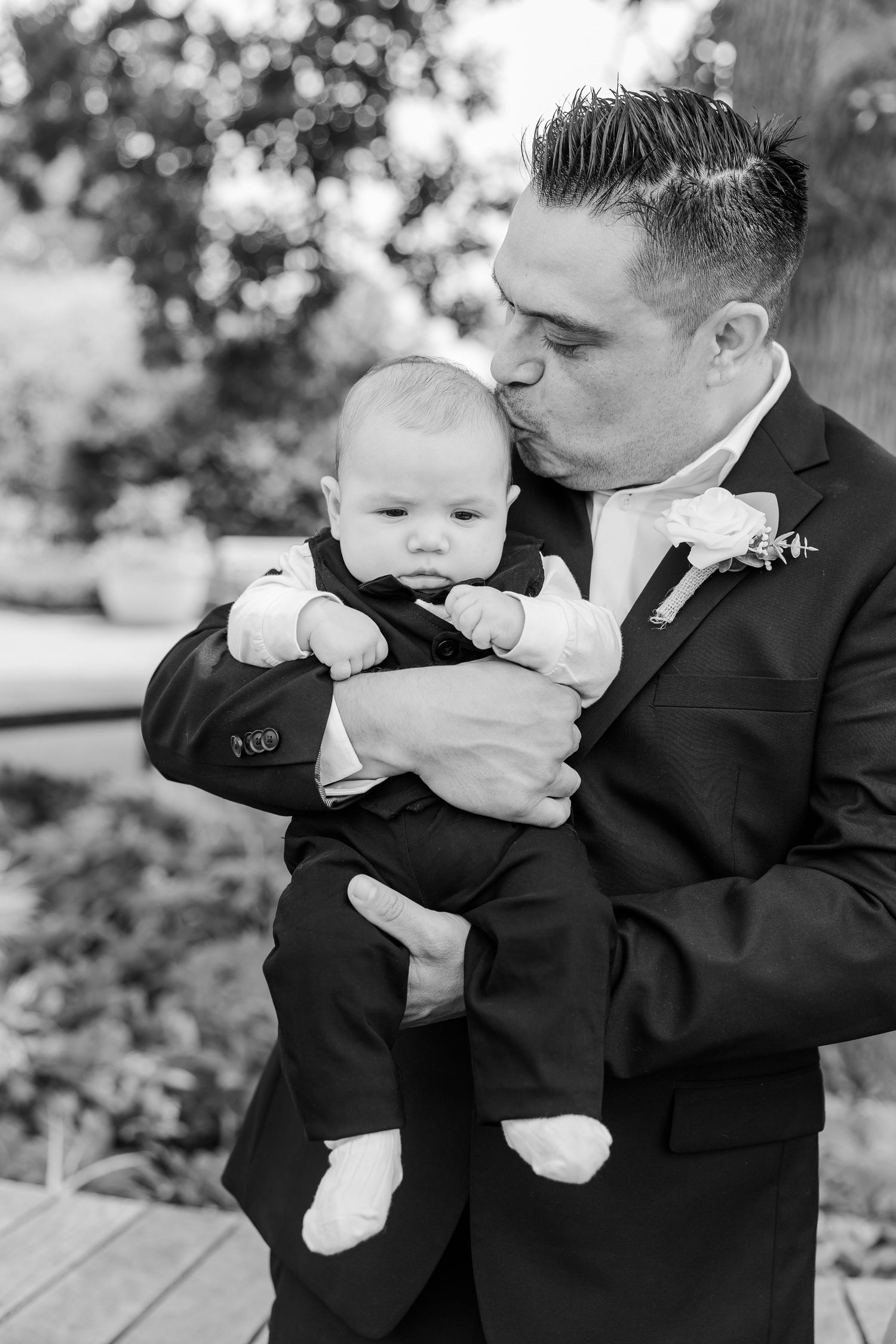Black-and-white portrait of the groom holding his baby during family photos at Cantigny Park.
