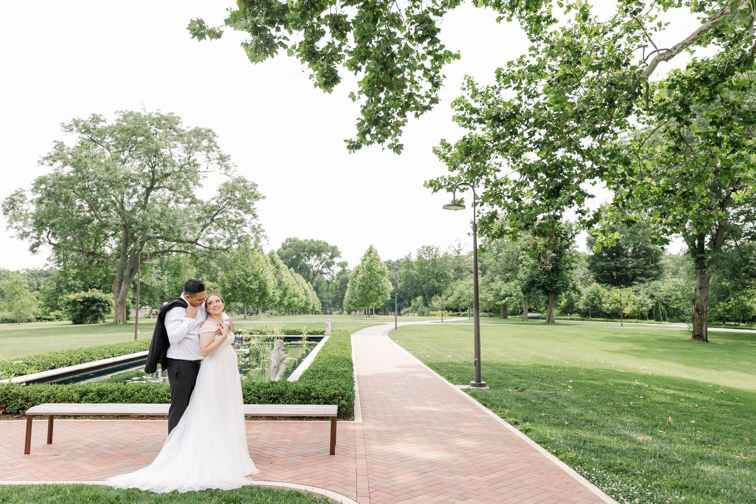 Wide portrait of Monika and Rafael embracing beside the formal gardens at Cantigny Park.