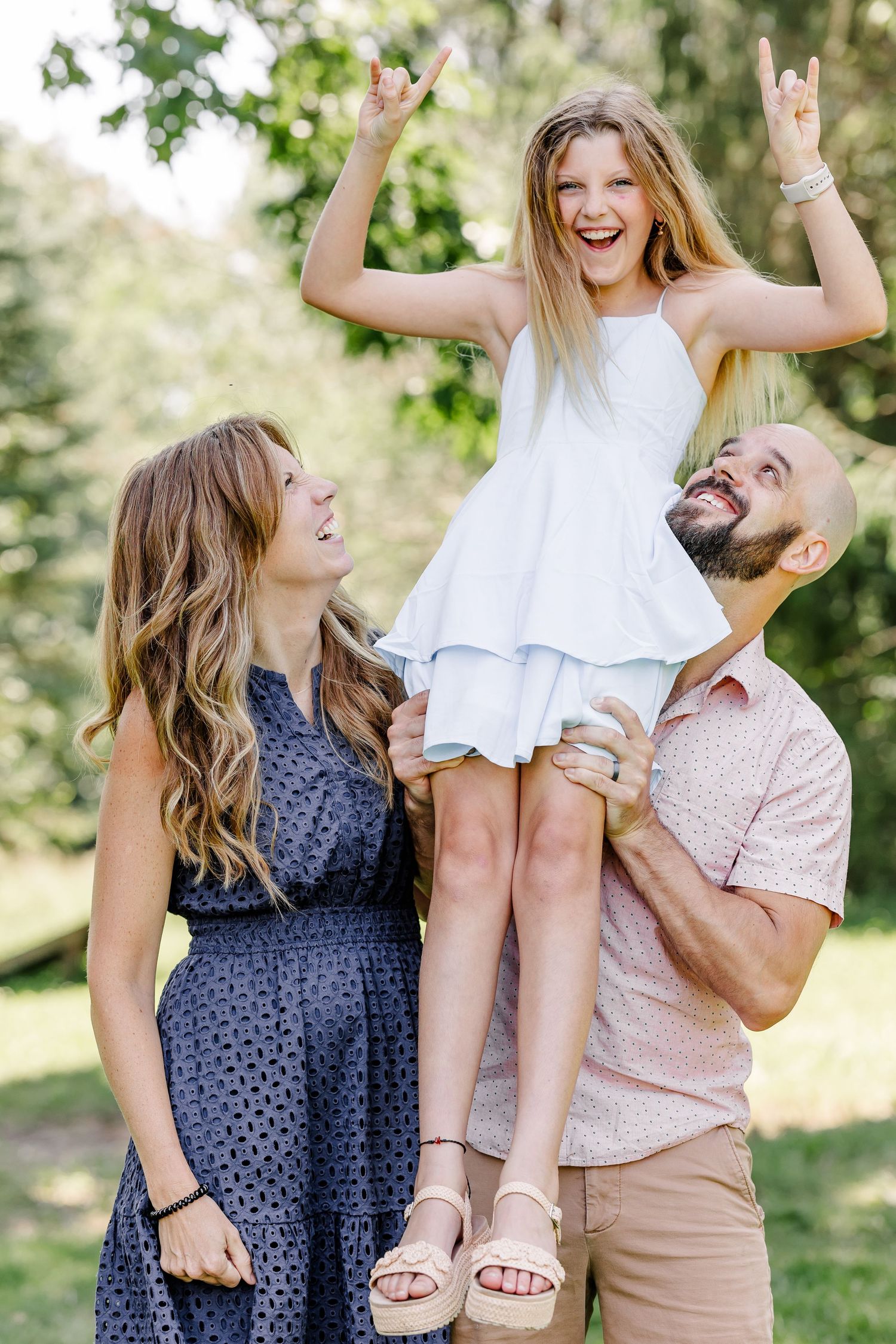 Parents lifting their daughter during a playful summer family portrait session in Crystal Lake, IL.