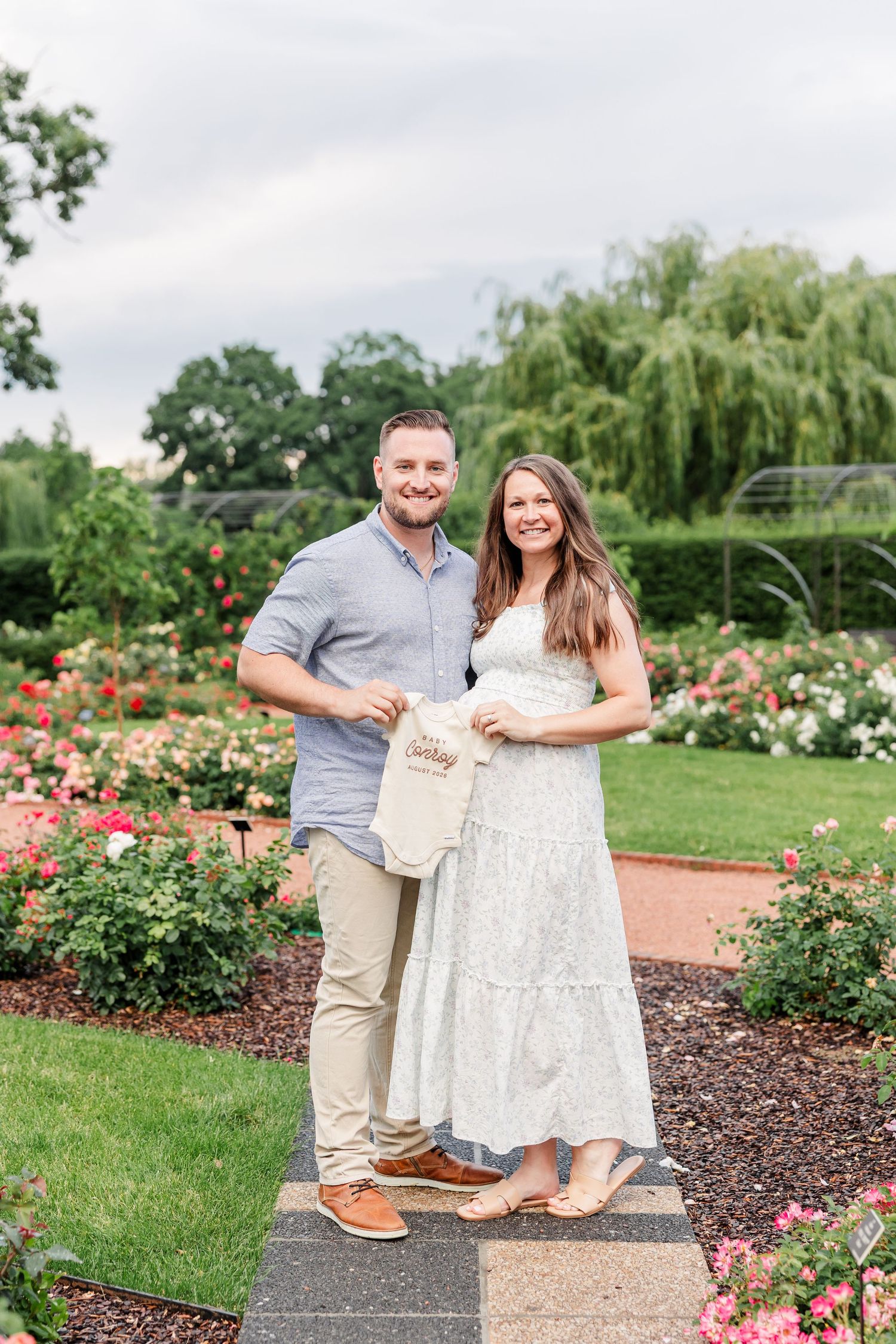 Expecting parents holding a baby outfit during a Cantigny Park maternity session