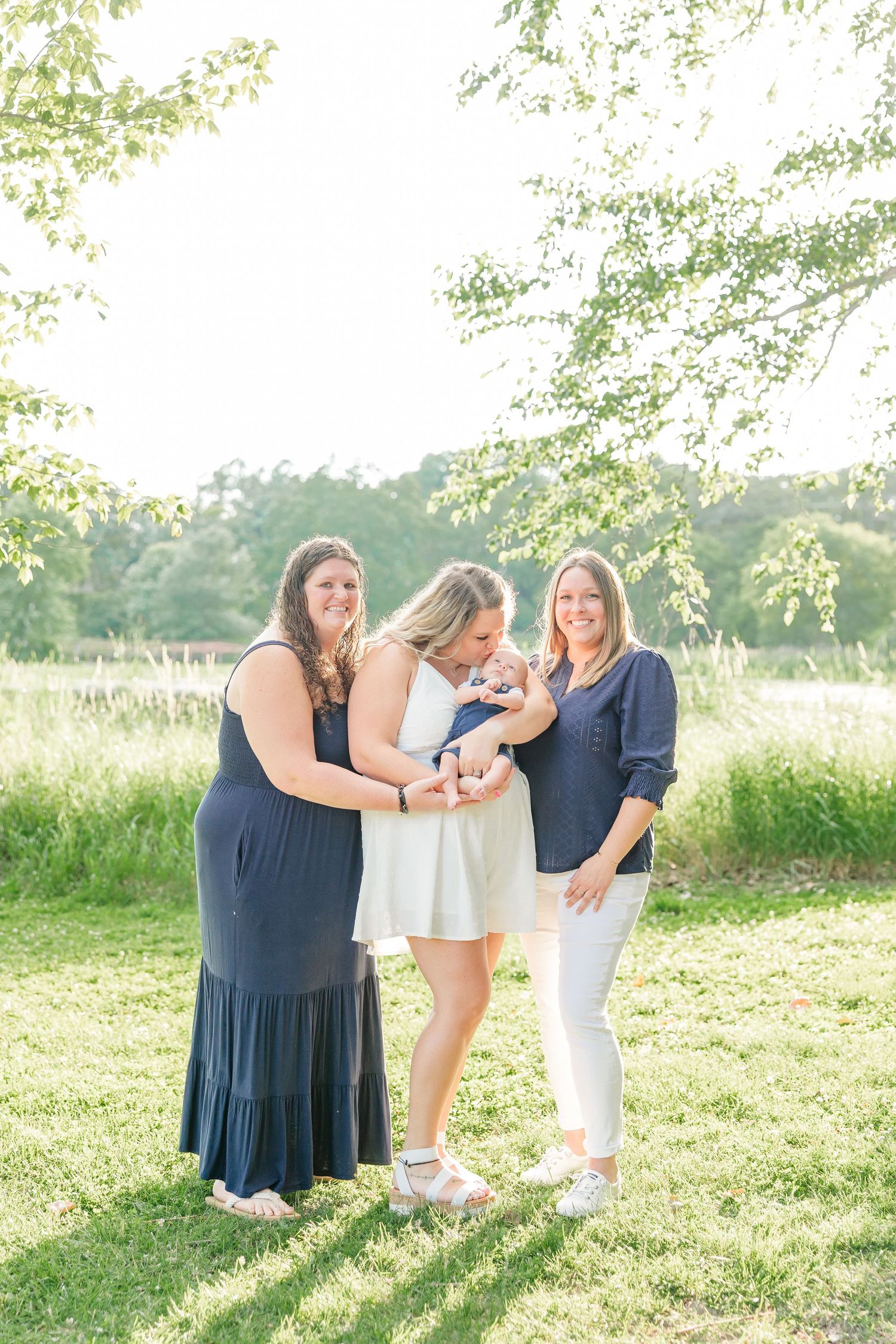 Women in the family loving on baby boy during a summer extended family photo session at Veterans Acres Nature Center