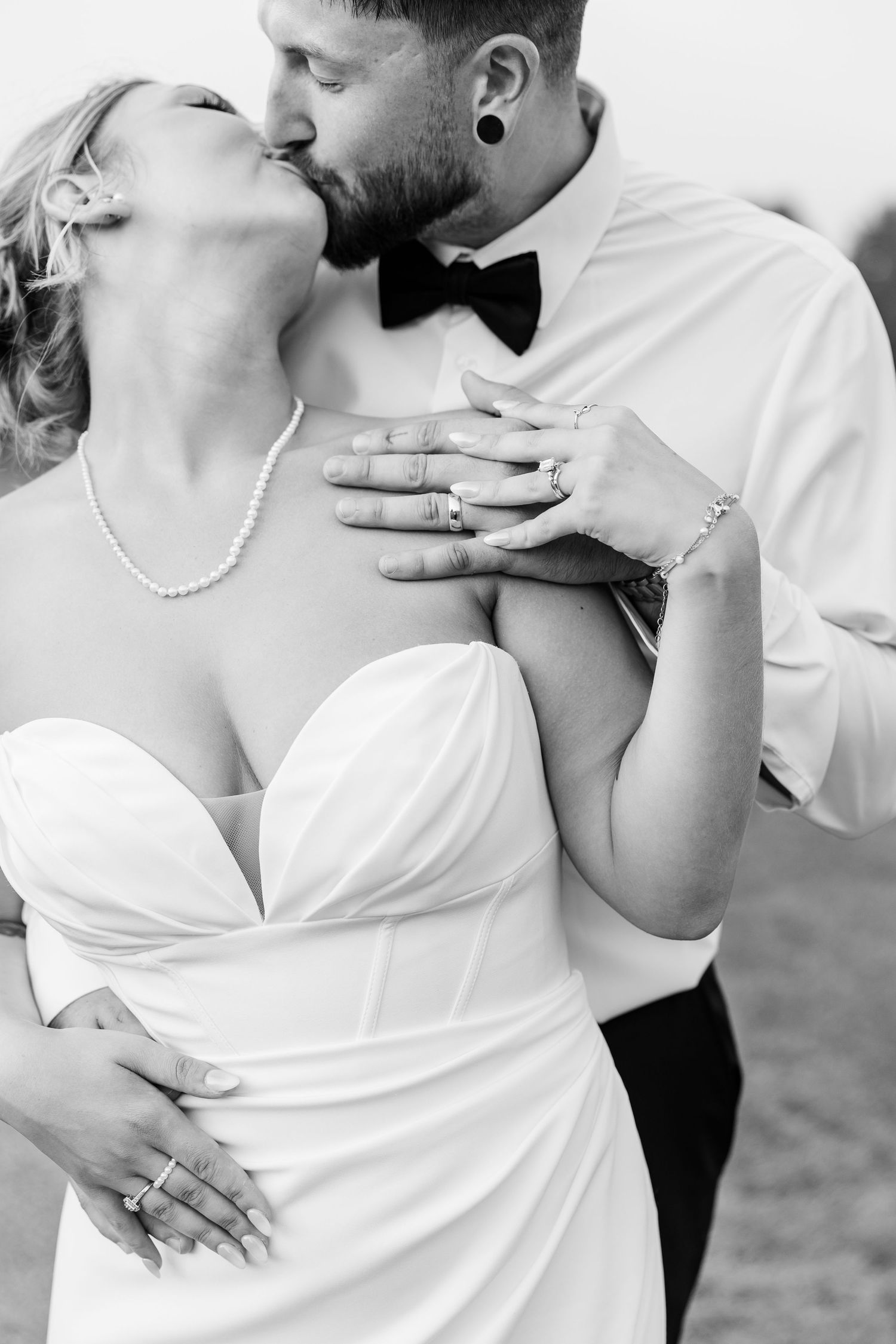 Black and white portrait of a bride and groom sharing a tender kiss during their wedding celebration.