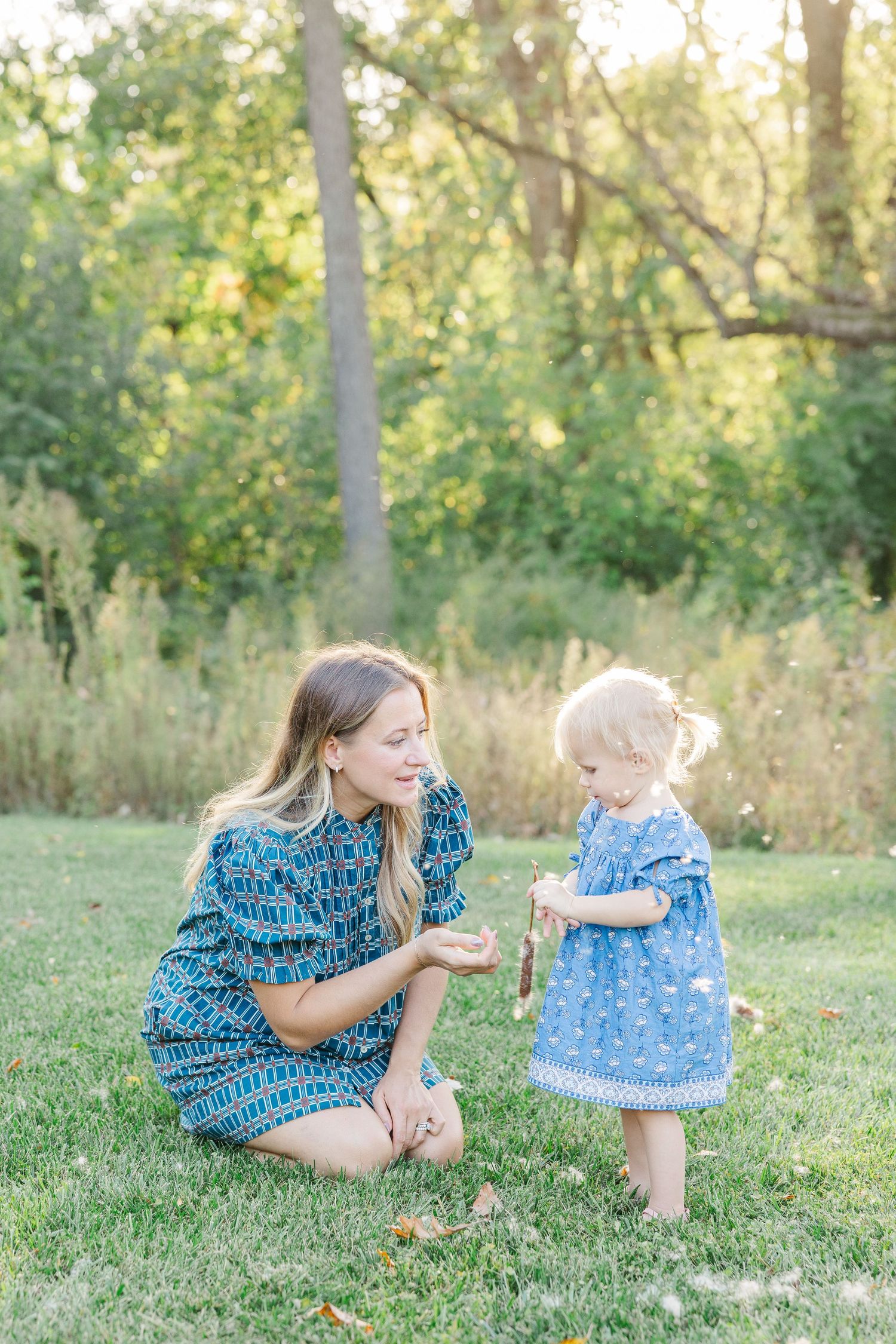 A heartwarming outdoor photo series showing a parent and baby in matching blue outfits playing together on green grass.