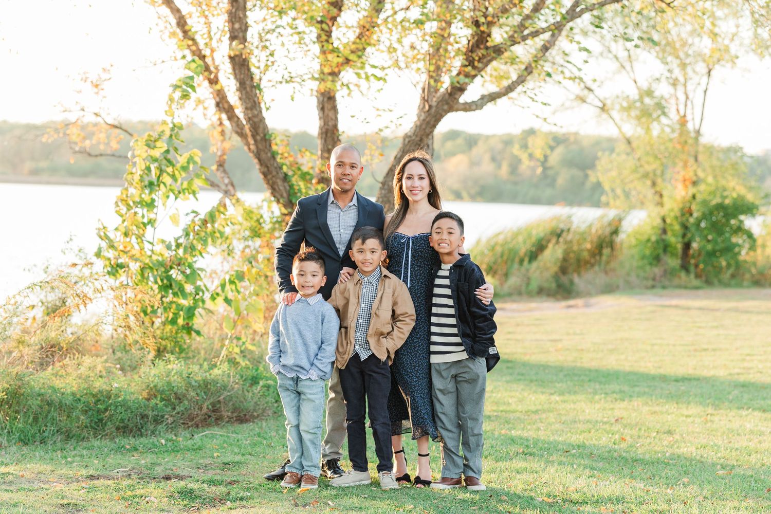 Family members stand together in a grassy field during golden hour sunset lighting. Busse Woods