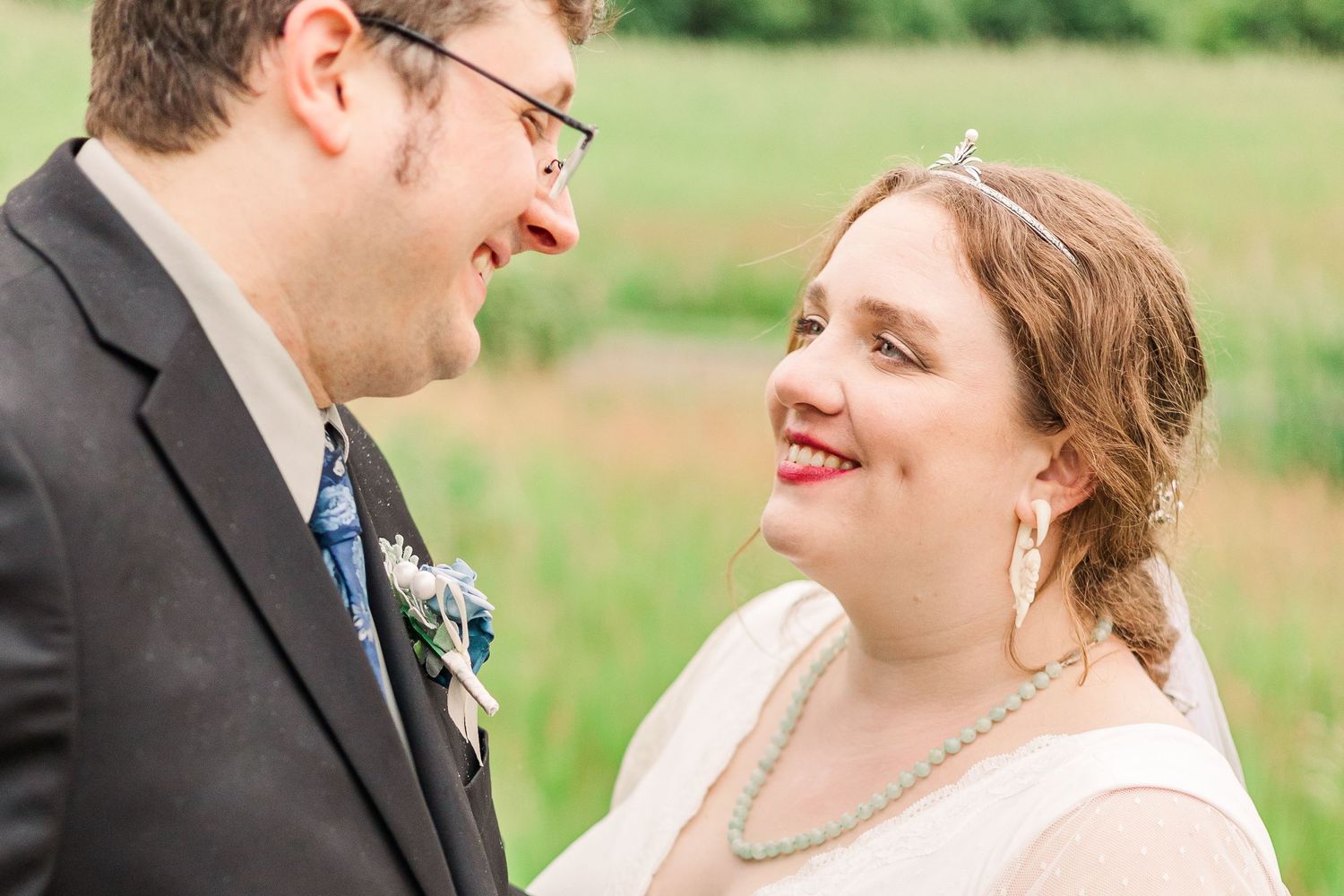 Joyful wedding couple shares a candid moment in a sunlit field.