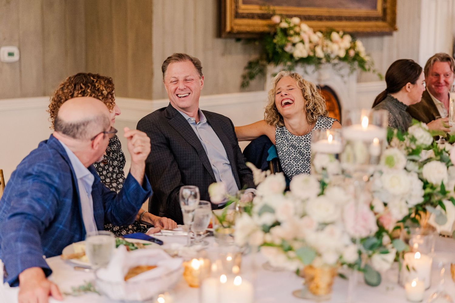Wedding reception guests sharing laughter at an elegantly decorated dining table.