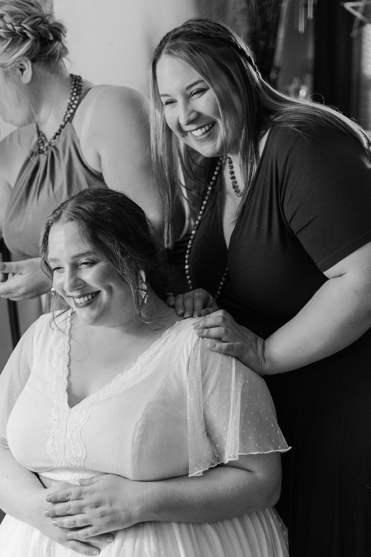 Black and white photo captures joyful moment between people in formal attire.