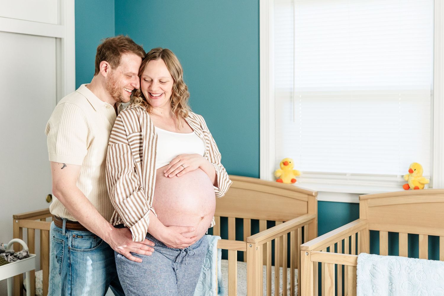 In-home maternity session in Crystal Lake with parents standing together in their twin boys’ nursery.