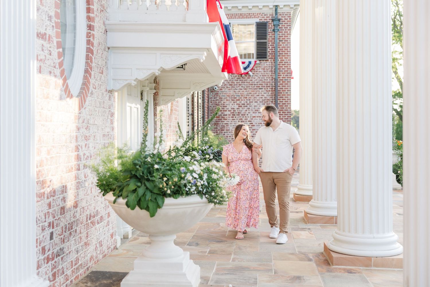 Parents-to-be walking along the brick courtyard during a summer maternity session at Cantigny Park