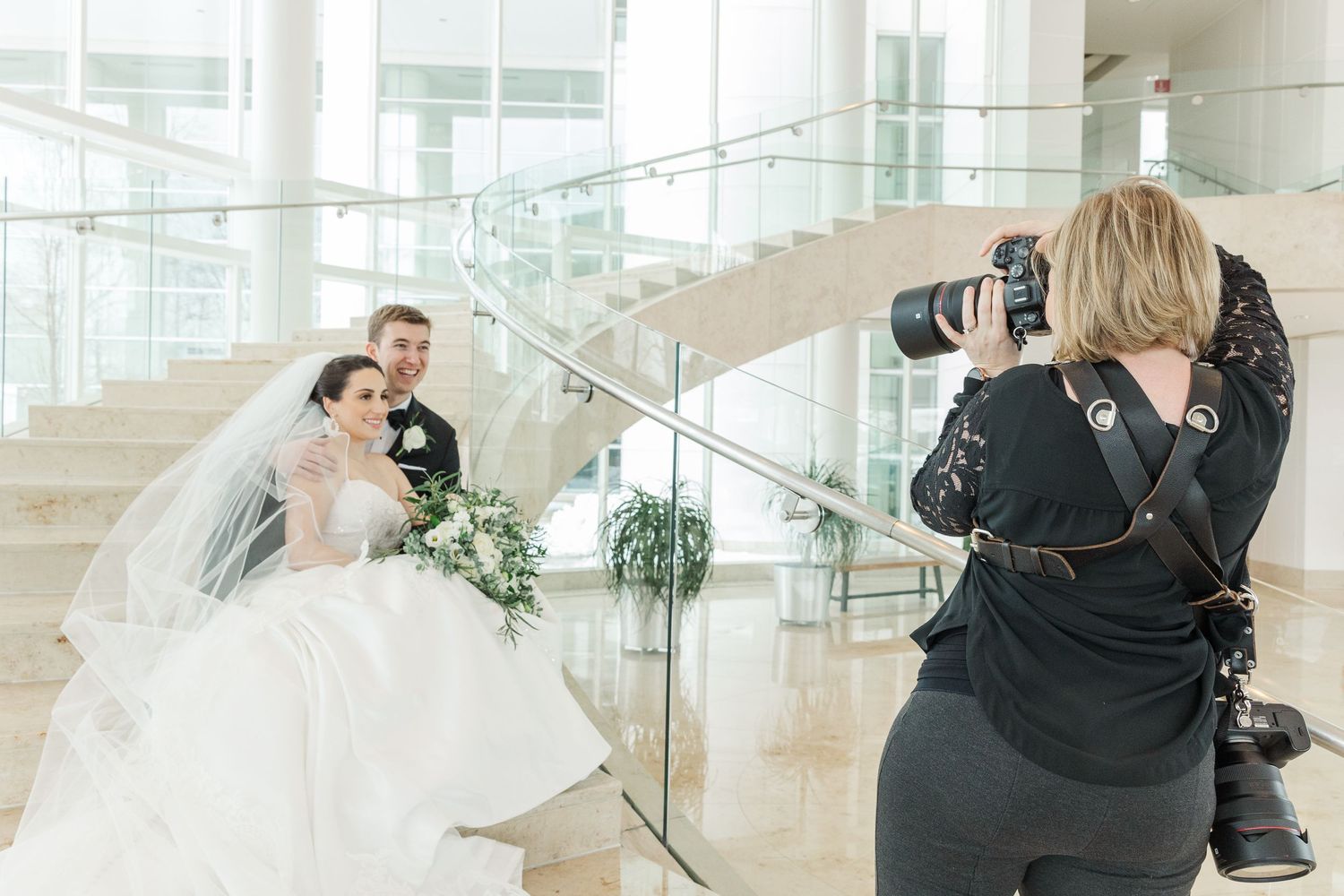Cassie Lacina photographing a bride and groom on a staircase during wedding portraits